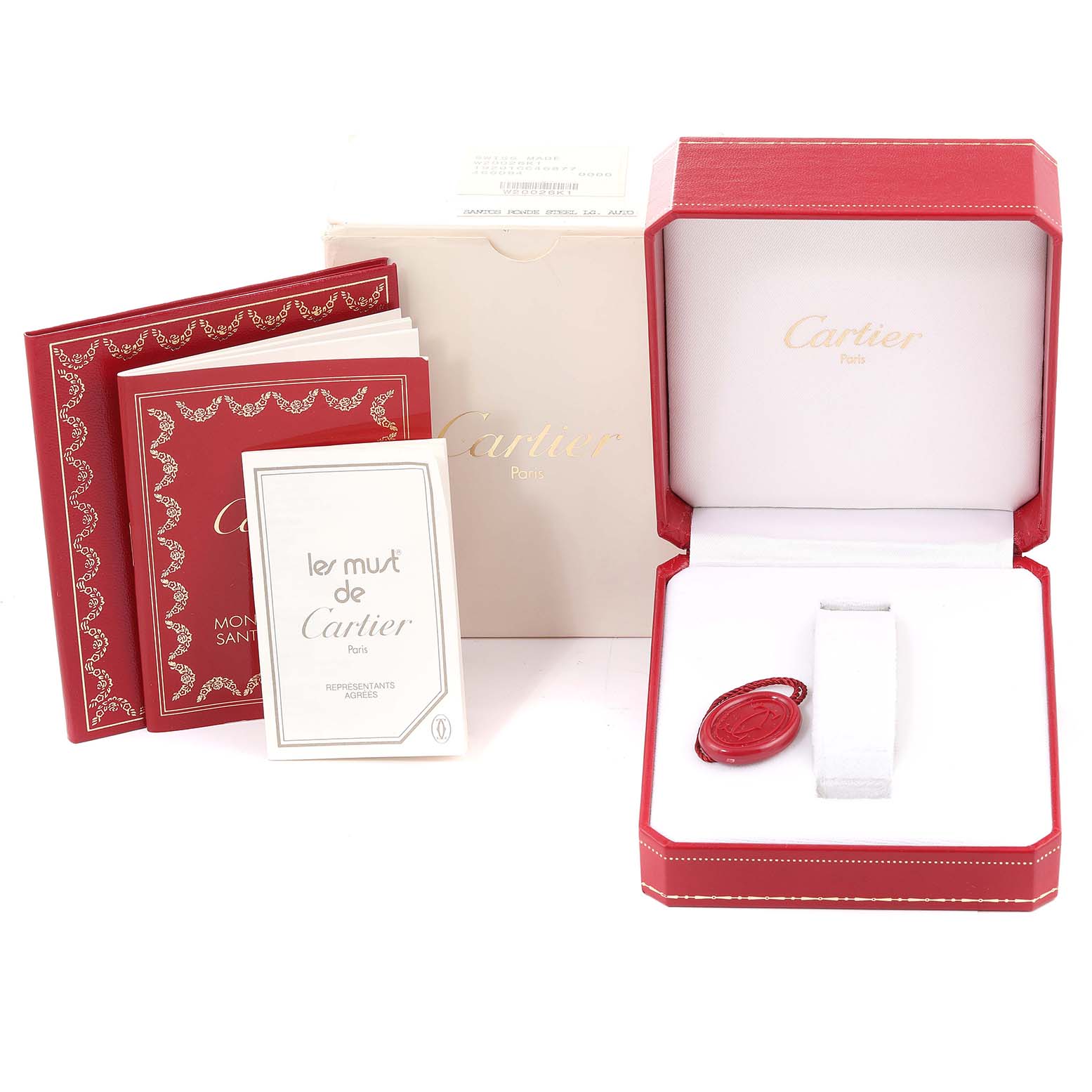 The image shows the packaging and accessories for a Santos model by Cartier, including the red box, manuals, and a tag.