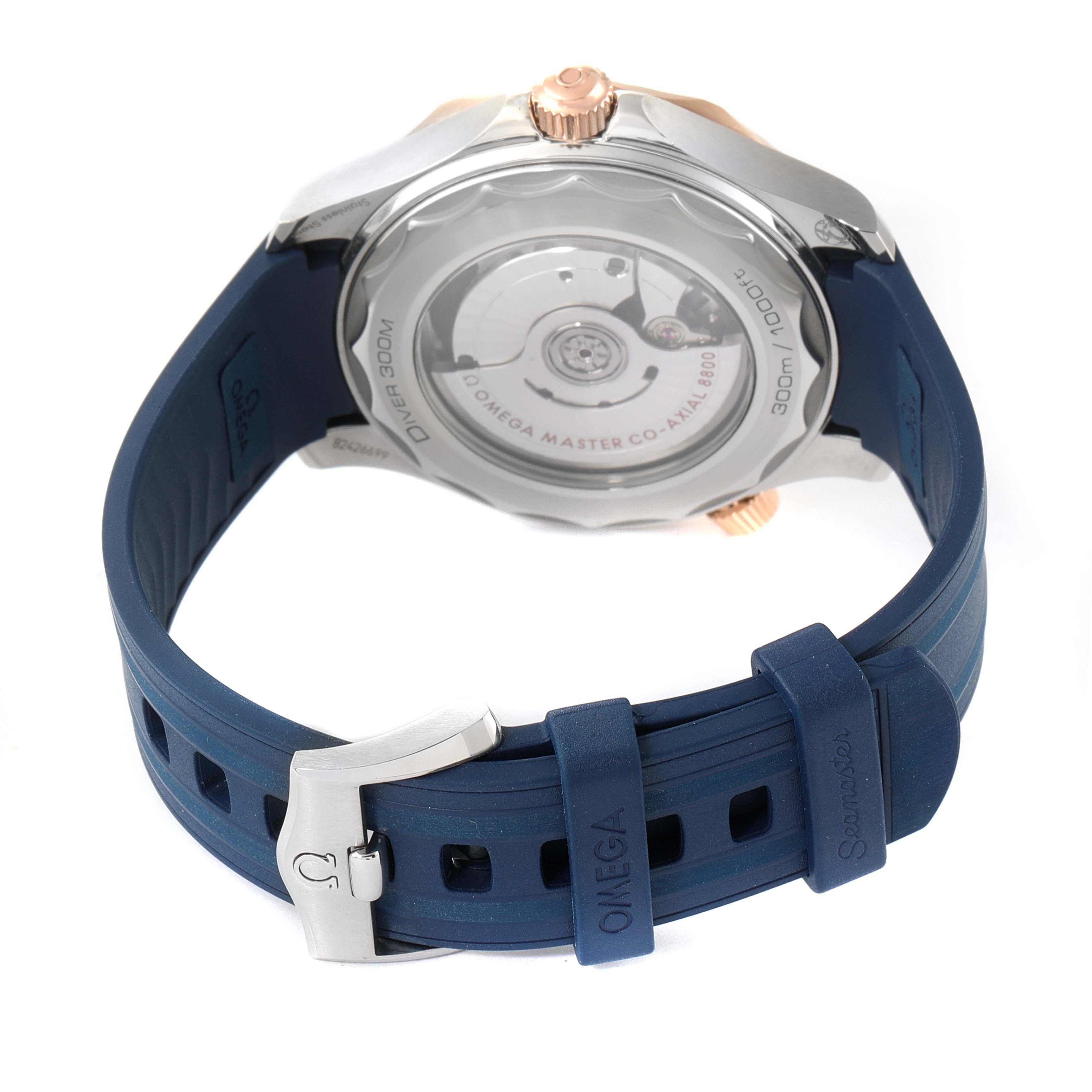 The image shows the back view of the Omega Seamaster 210.22.42.20.03.002 Men's Steel and Gold (two tone) Blue Dial 210.22.42.20.03.002 Men's Steel and Gold (two tone) Blue Dial watch, highlighting the case back, rotor, and blue rubber strap with buckle.