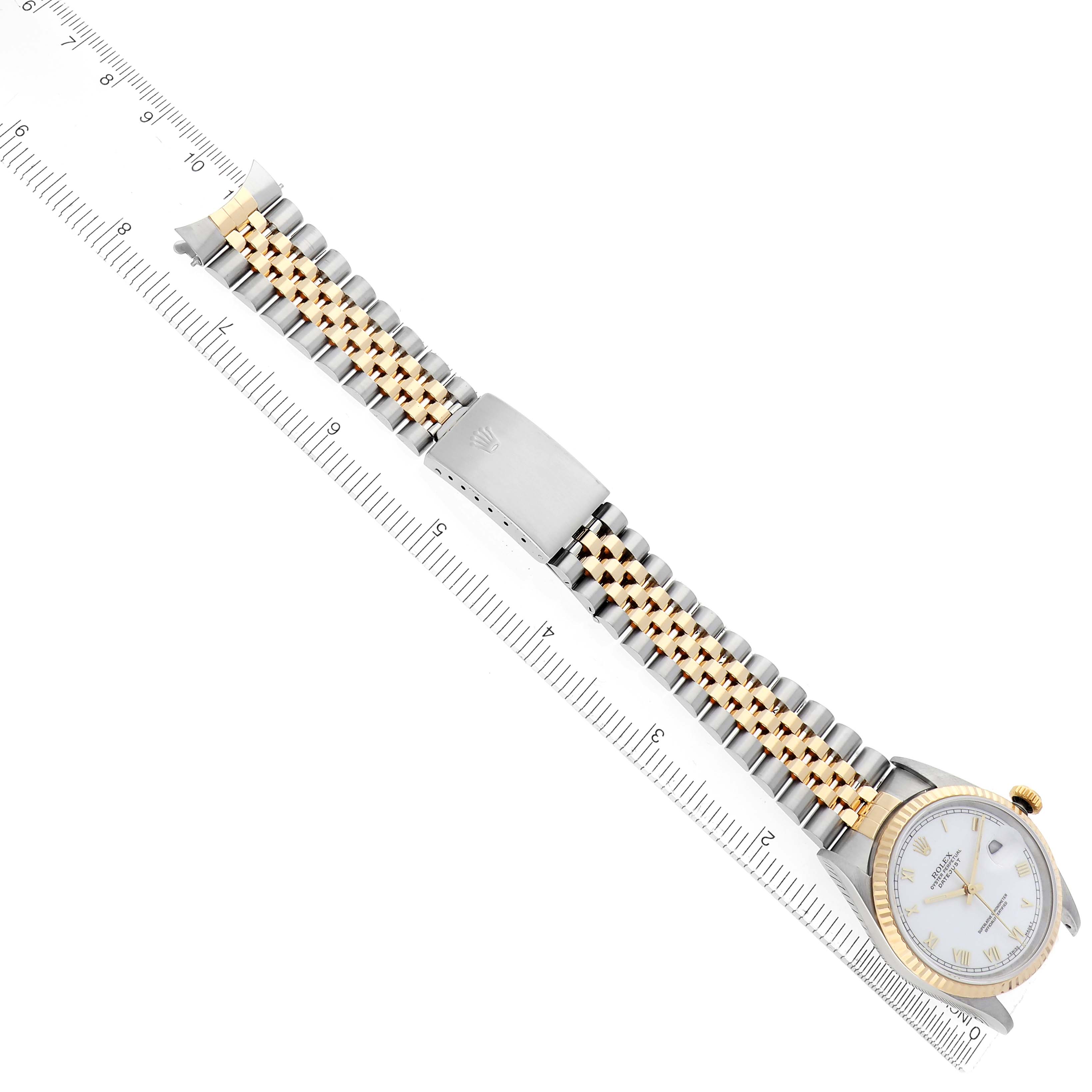 The Rolex Datejust model 16233 is shown from a top-down angle, displaying the watch face, bezel, and two-tone bracelet clearly aligned with a ruler.
