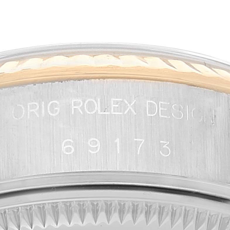 The image shows the side view of a Rolex Datejust 69173 Women
s Steel and Gold (two tone) White Dial 69173 Women
s Steel and Gold (two tone) White Dial model, highlighting the engraved "ORIG ROLEX DESIGN" and model number "69173" on the case.