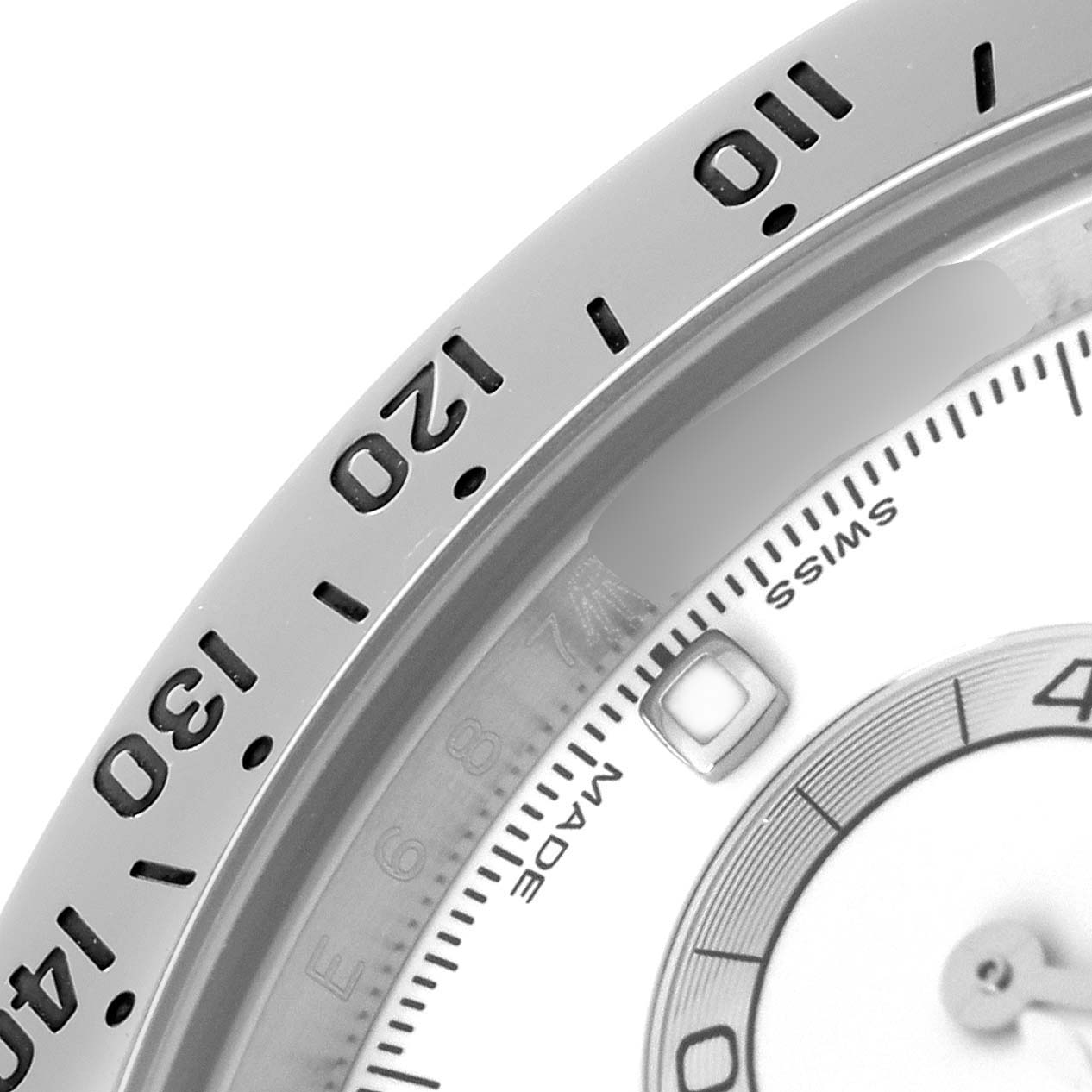 The image shows a close-up of the bezel and partial dial of a Rolex Daytona model 116520, highlighting the tachymetric scale and part of the dial.