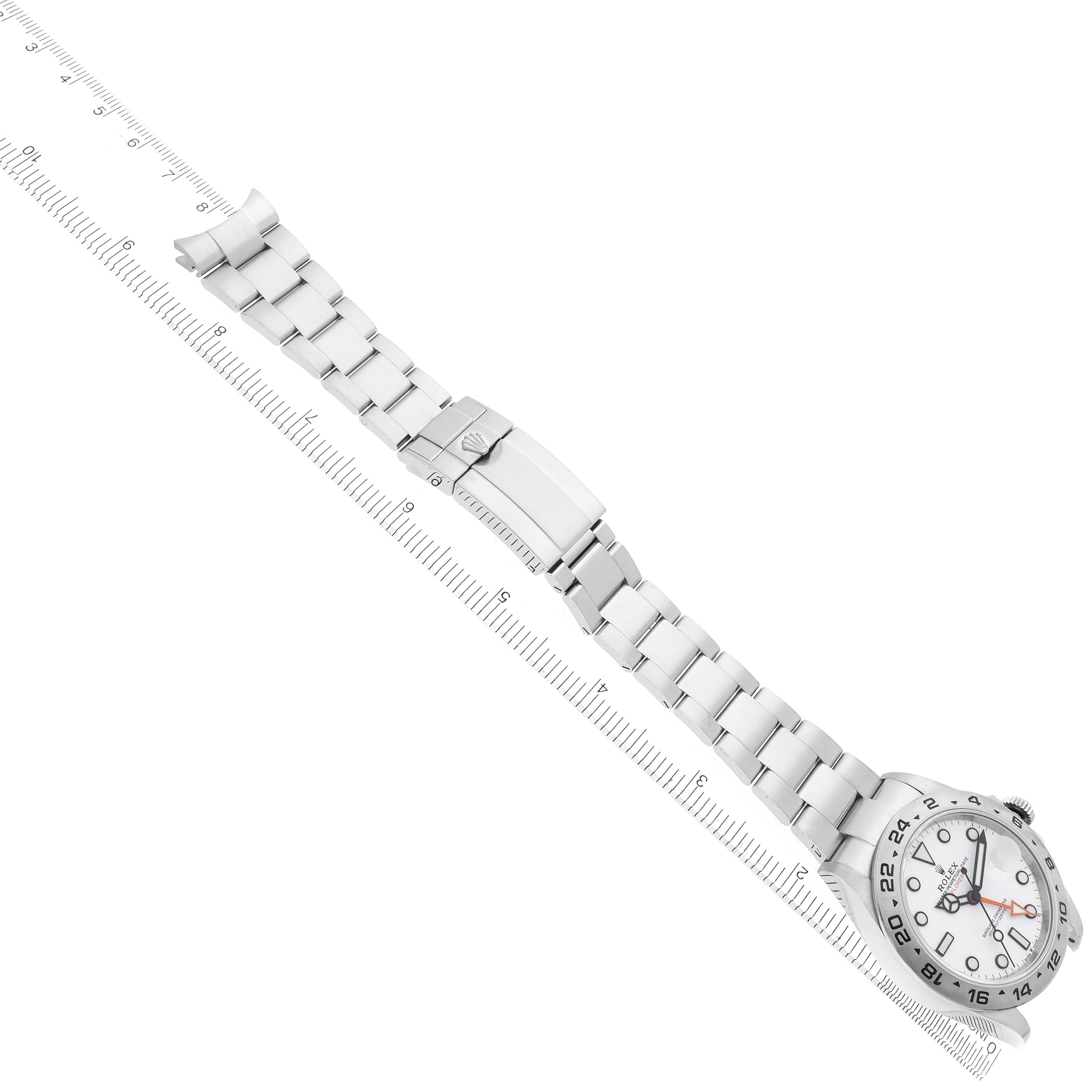 The Rolex Explorer model 226570 watch is shown laid flat, featuring the face, bezel, bracelet, and clasp aligned with a ruler for scale.