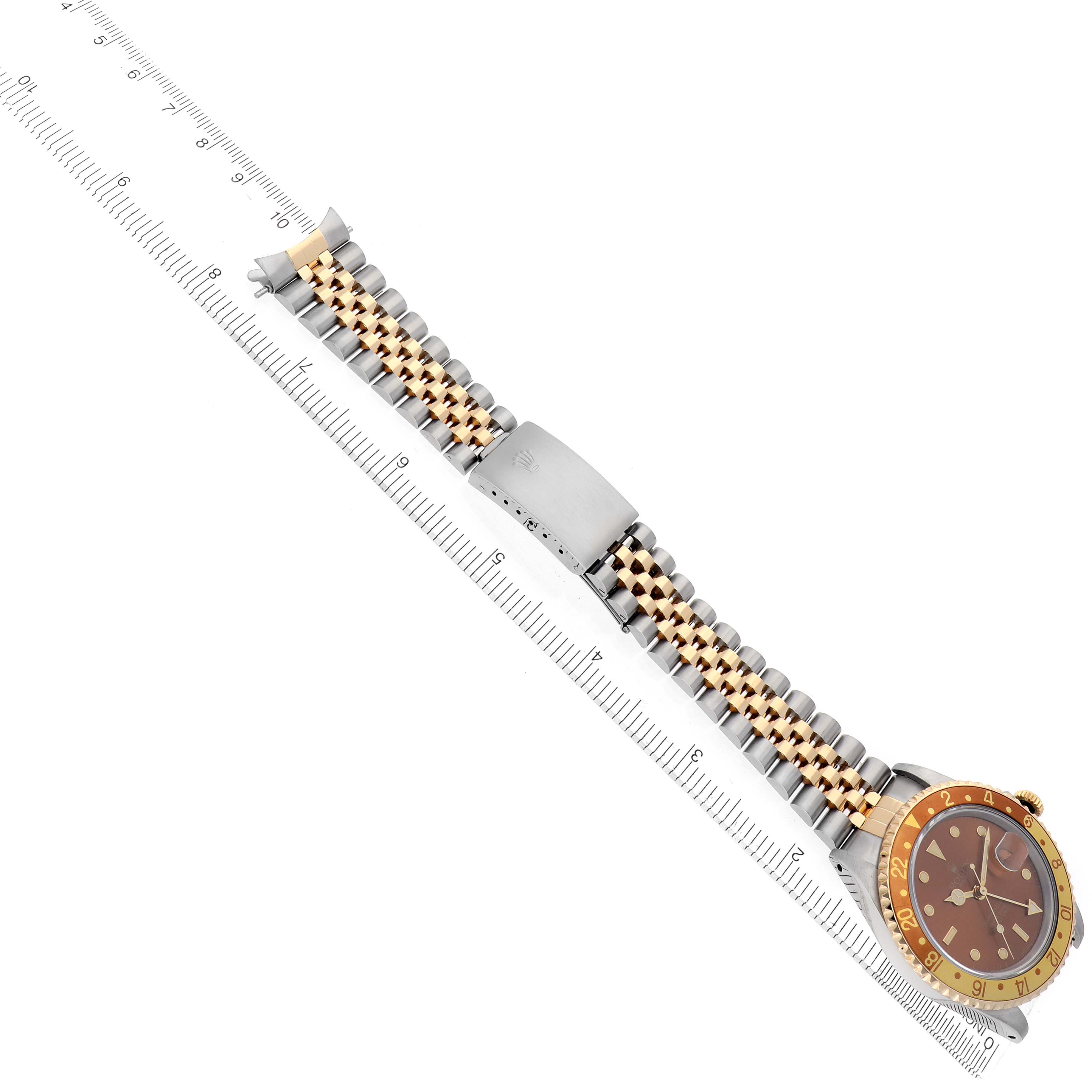 The image shows a Rolex GMT-Master model 16713, displaying the watch face at an angle along with its two-tone bracelet and clasp, alongside a ruler for scale.