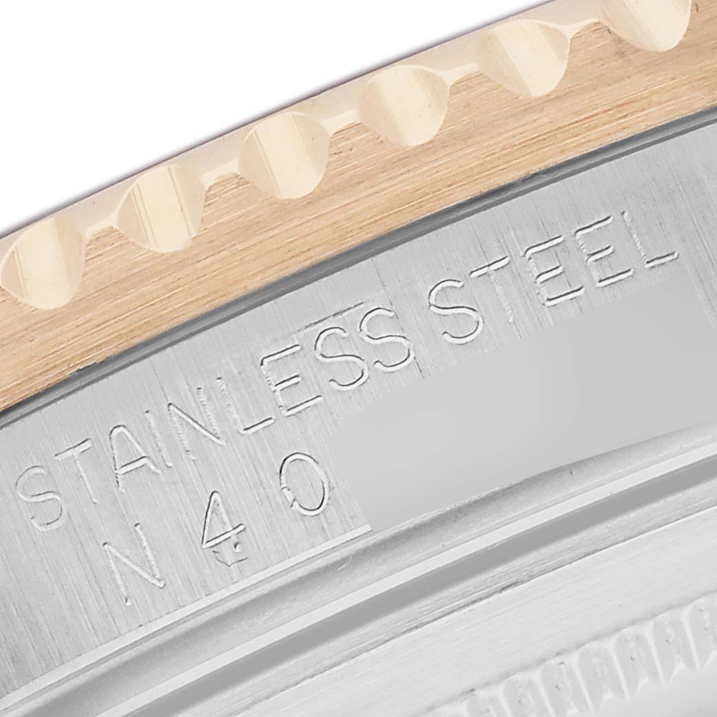 The image shows a close-up of the Rolex GMT-Master model 16713, focusing on the textured edge of the bezel and stainless steel case back with engraved text.