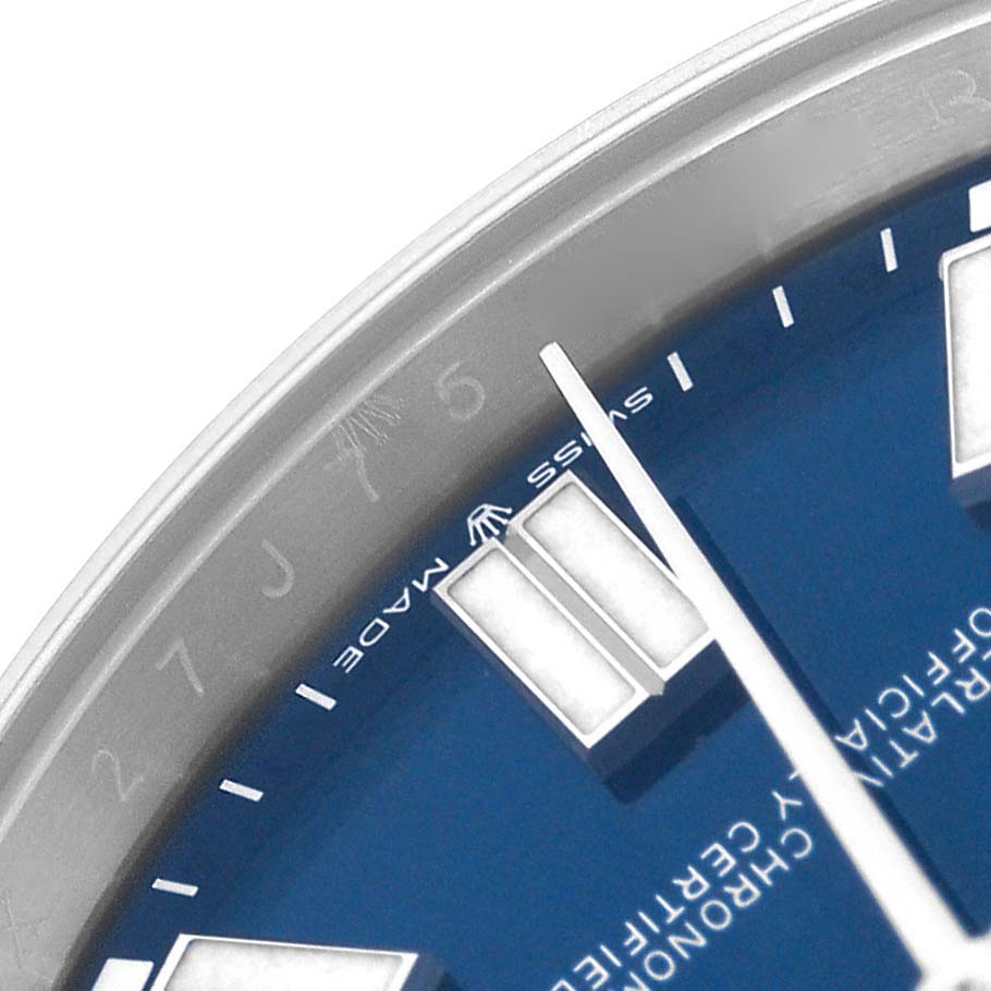 The image shows a close-up of the dial and part of the bezel of a Rolex Oyster Perpetual model 124300, highlighting the blue face and markers.