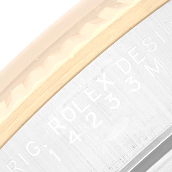 This close-up image shows the engraved side of a Rolex Oyster Perpetual 14233 Men's Steel and Gold (two tone) Champagne Dial 14233 Men's Steel and Gold (two tone) Champagne Dial watch bezel.