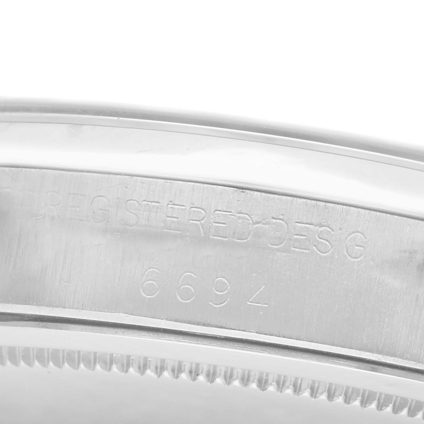 The image shows a close-up of the case edge on a Rolex Date model, model number 6694, with engraved design and the model number visible.
