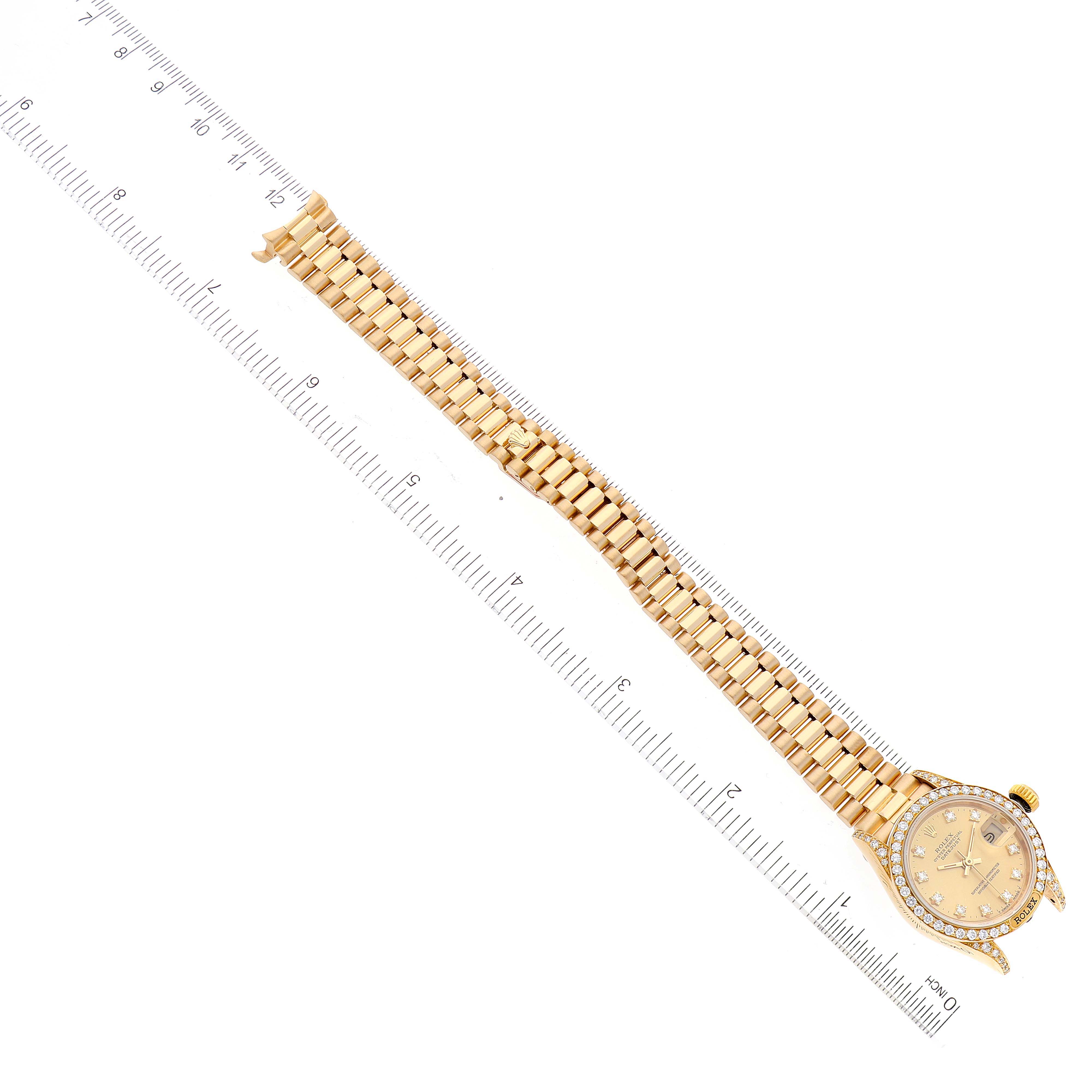 This image shows a Rolex President 69158 Women
s Yellow Gold Champagne Dial 69158 Women
s Yellow Gold Champagne Dial model watch laid flat alongside a ruler, displaying its face and entire bracelet.
