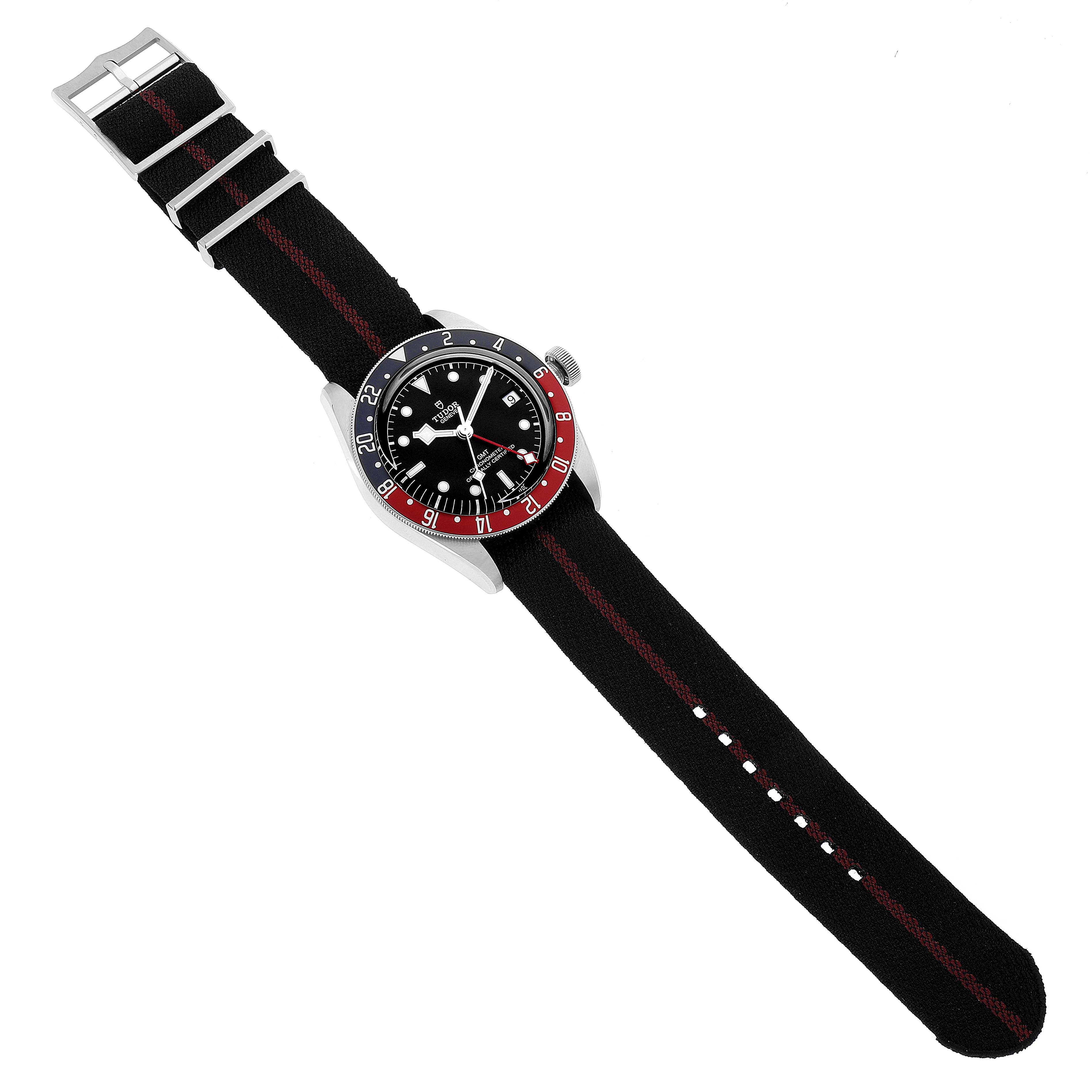 The image shows a Tudor Heritage Black Bay 79830RB Men's Stainless Steel Black Dial 79830RB Men's Stainless Steel Black Dial watch laid flat with a black and red striped fabric strap, viewed from above.