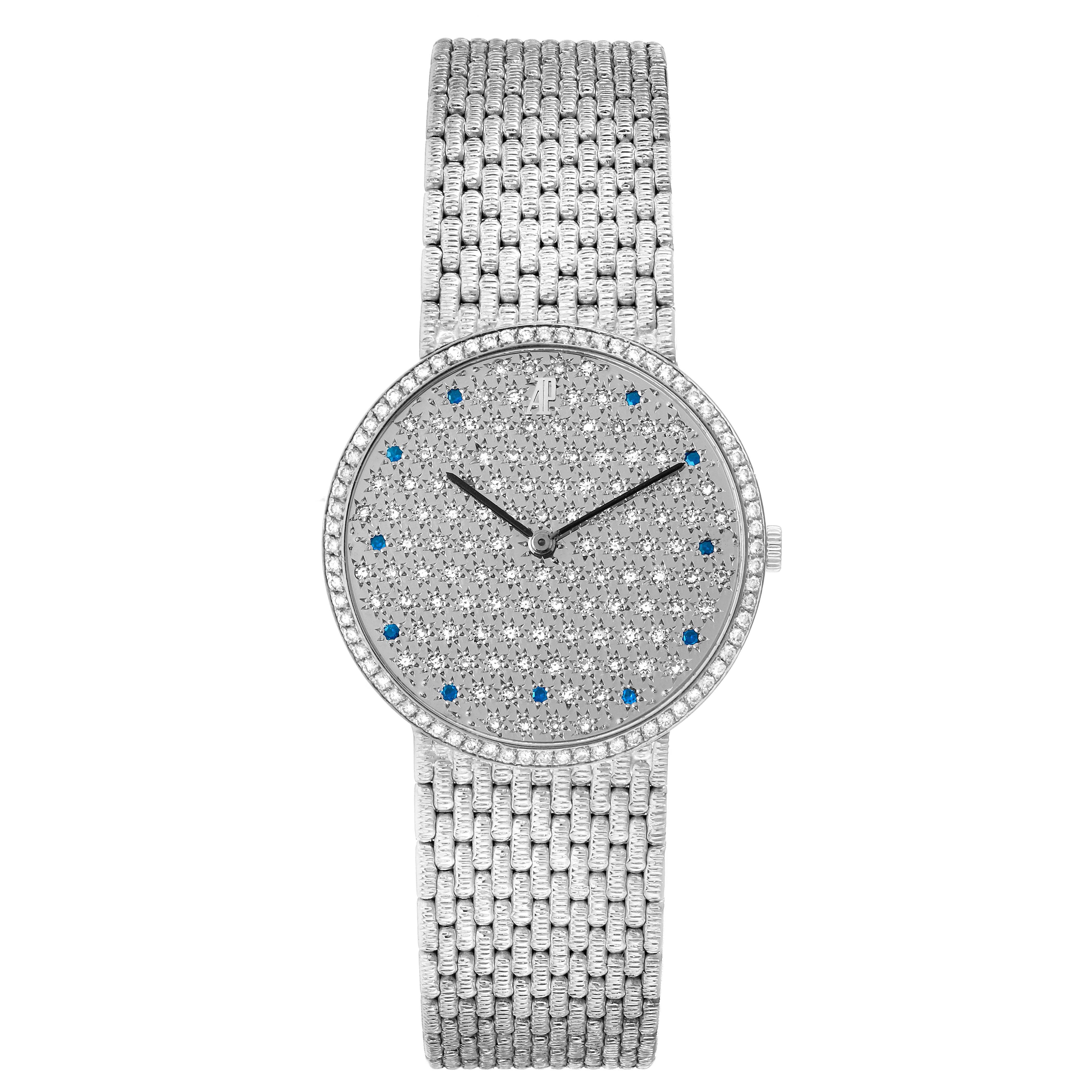 The Audemars Piguet Vintage model watch is shown from a top-down angle, highlighting its round white gold case, diamond and sapphire-studded dial, and woven bracelet.