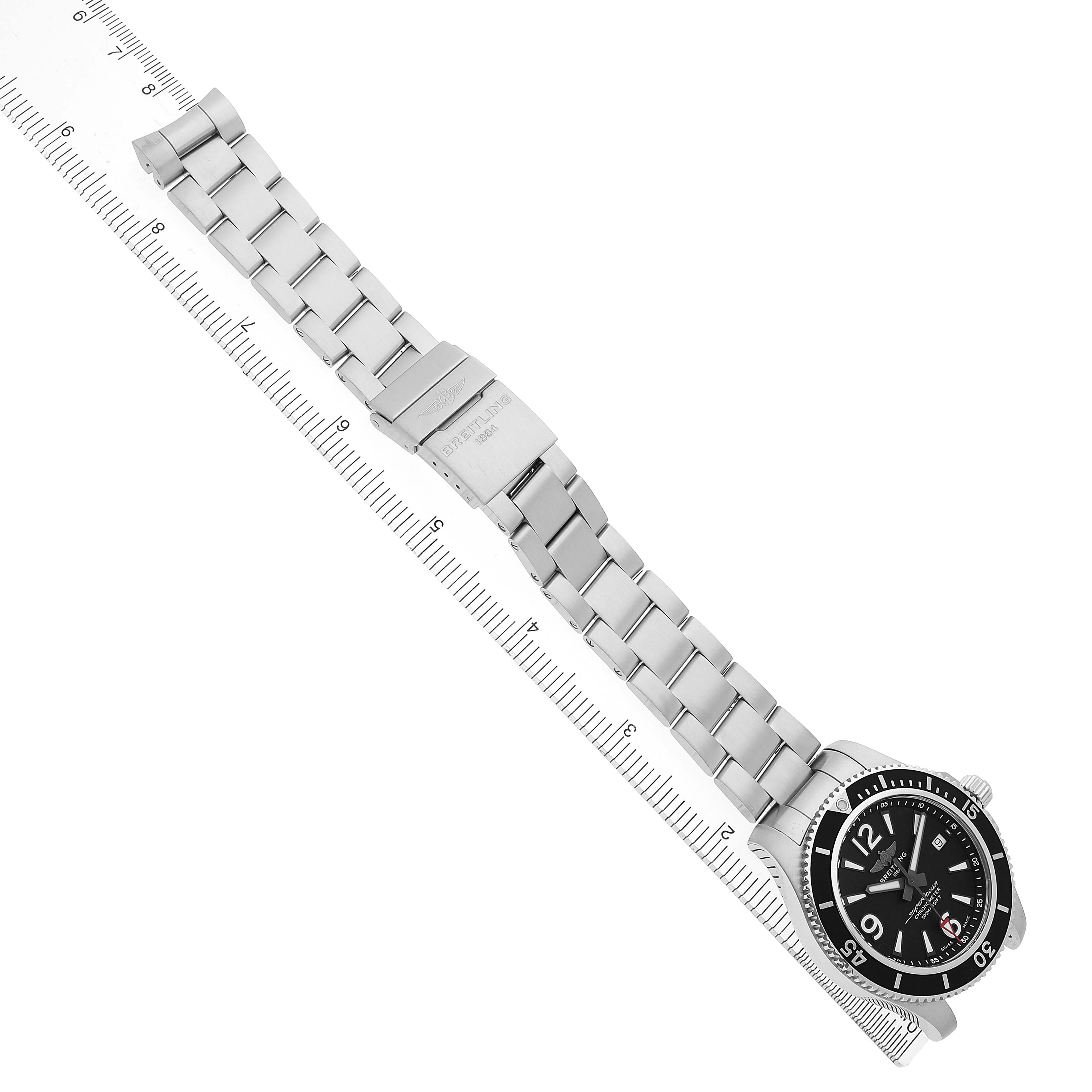 The Breitling Superocean A17366 Men's Stainless Steel Black Dial watch is shown from an overhead angle, displaying the full stainless steel bracelet and face against a ruler.