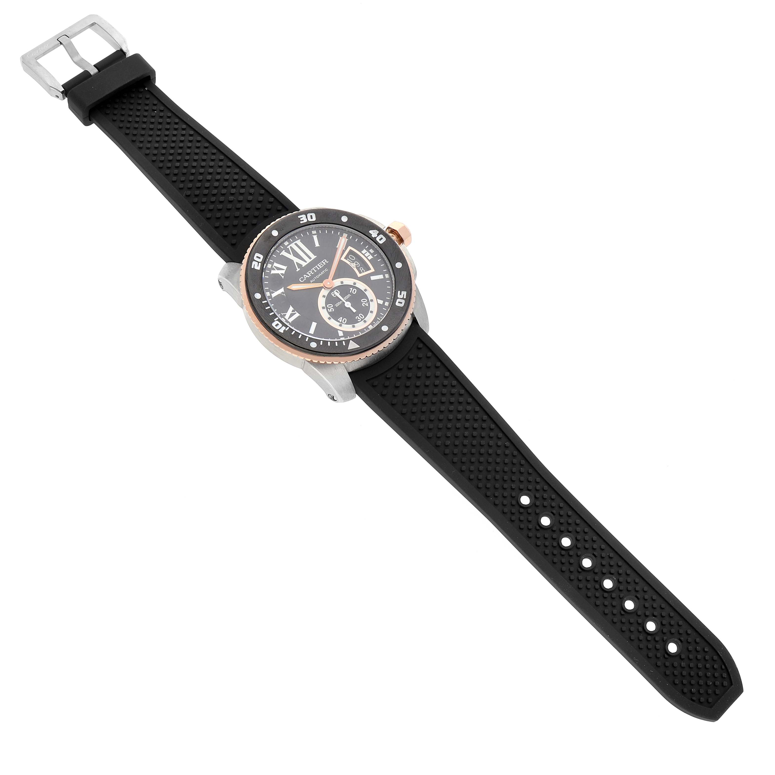 The Calibre de Cartier watch is shown from a top-down angle, highlighting its black dial, rose gold bezel, and black rubber strap.