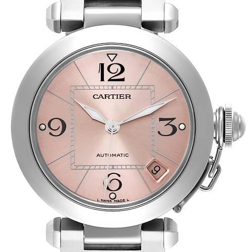 The image shows a front view of the Cartier Pasha watch, highlighting its pink dial, date window at 4 o'clock, and metallic case.