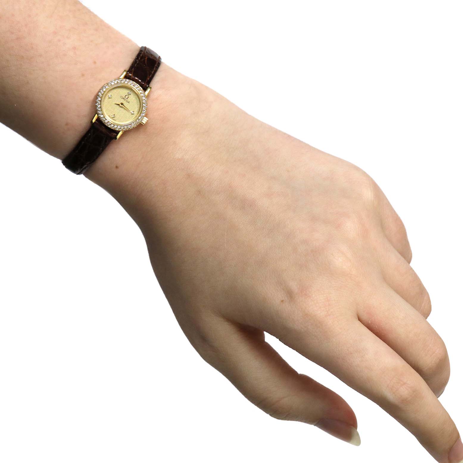 The image shows an Omega 1450 Women
s Yellow Gold Champagne Dial 1450 Women
s Yellow Gold Champagne Dial DeVille Mini Yellow Gold Diamond Cocktail Ladies Watch 1450 being worn on a wrist, viewed from above.