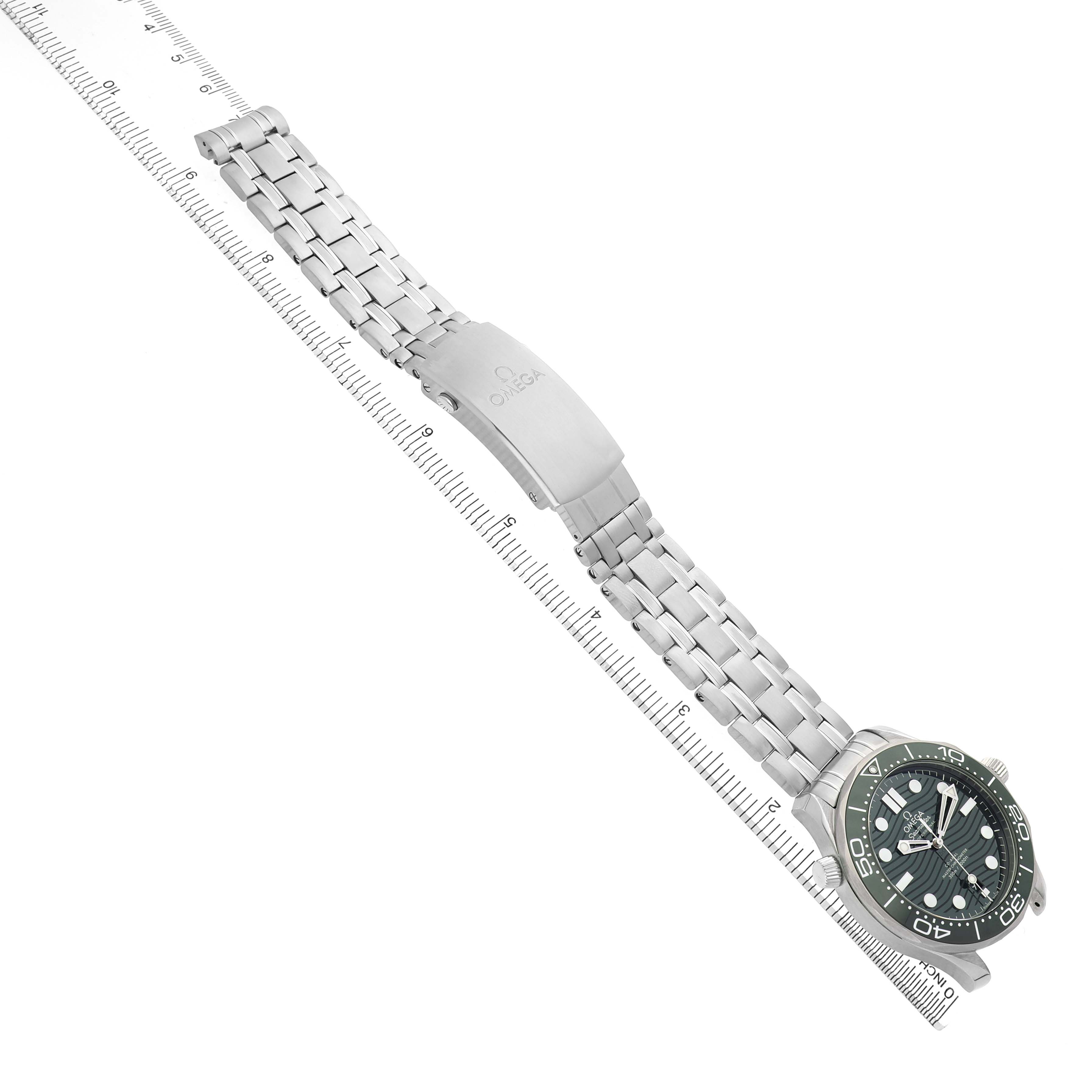 The Omega Seamaster 210.32.42.20.10.001 Men's Stainless Steel Green Dial watch is shown from a top-down angle, displaying the face, bracelet, and clasp next to a ruler for scale.