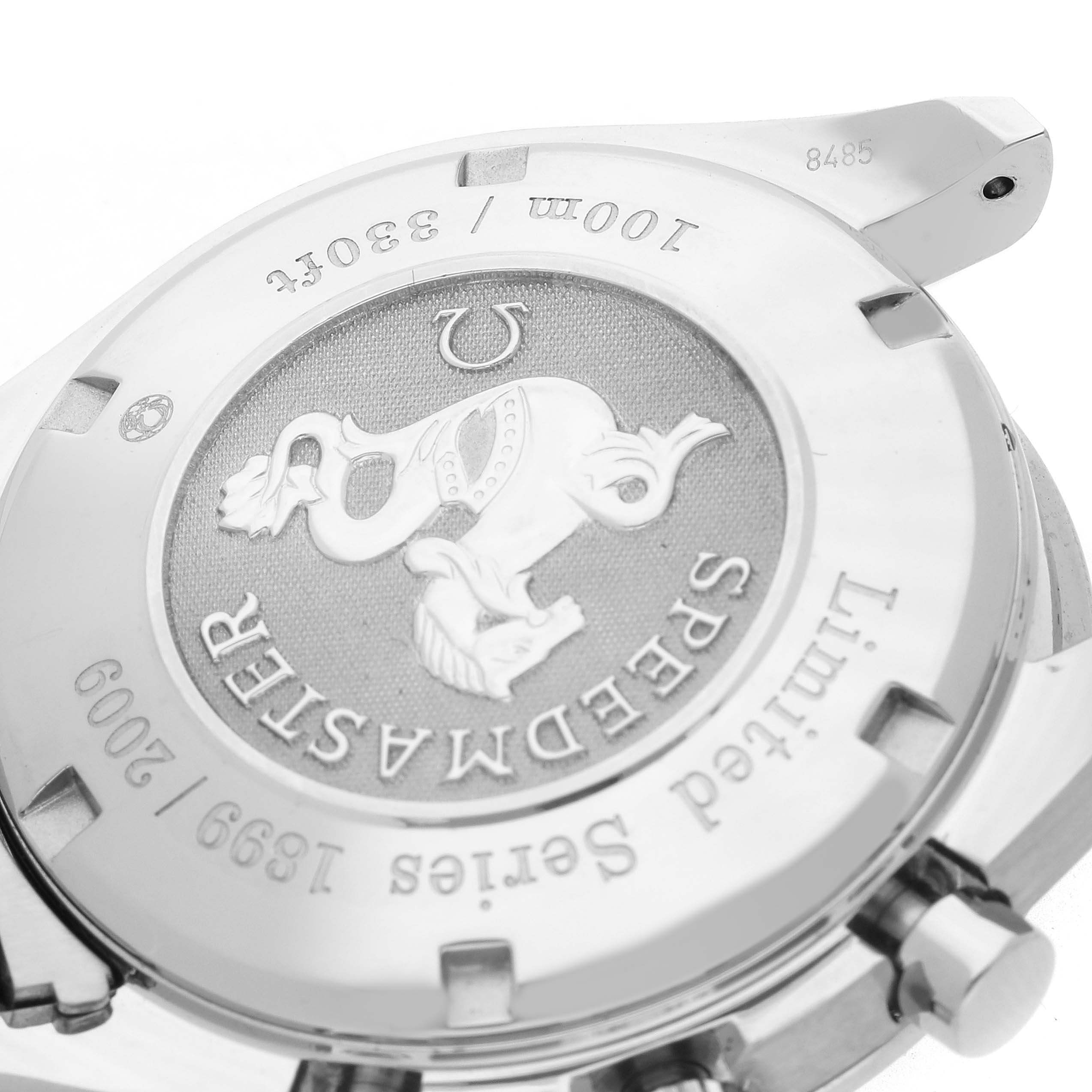 The image shows the case back of an Omega Speedmaster model 323.30.40.40.02.001, highlighting engraved details and decorative elements.