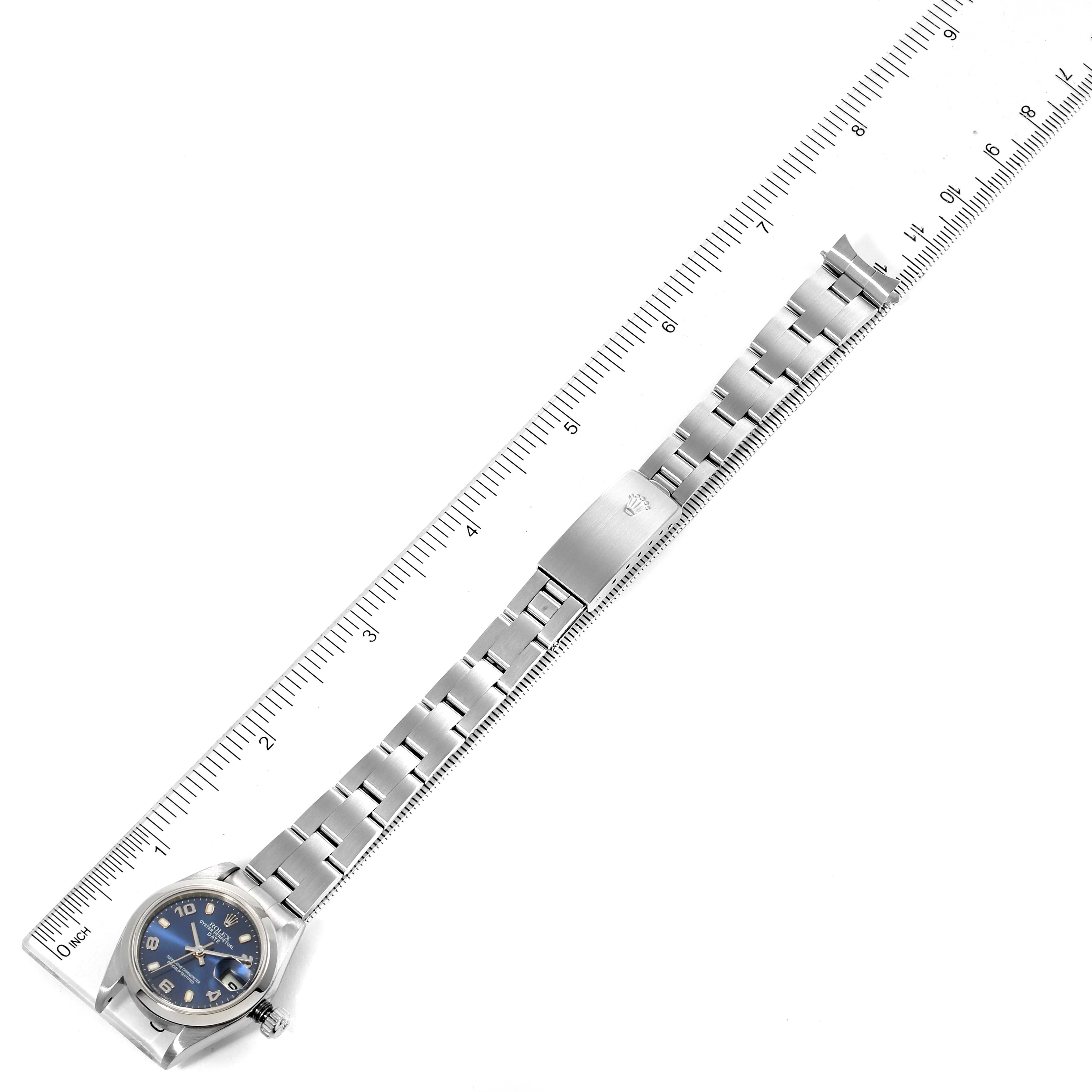 The image shows a Rolex Date 79160 Women
s Stainless Steel Blue Dial 79160 Women
s Stainless Steel Blue Dial watch with a blue dial and a stainless steel bracelet alongside a ruler for scale.