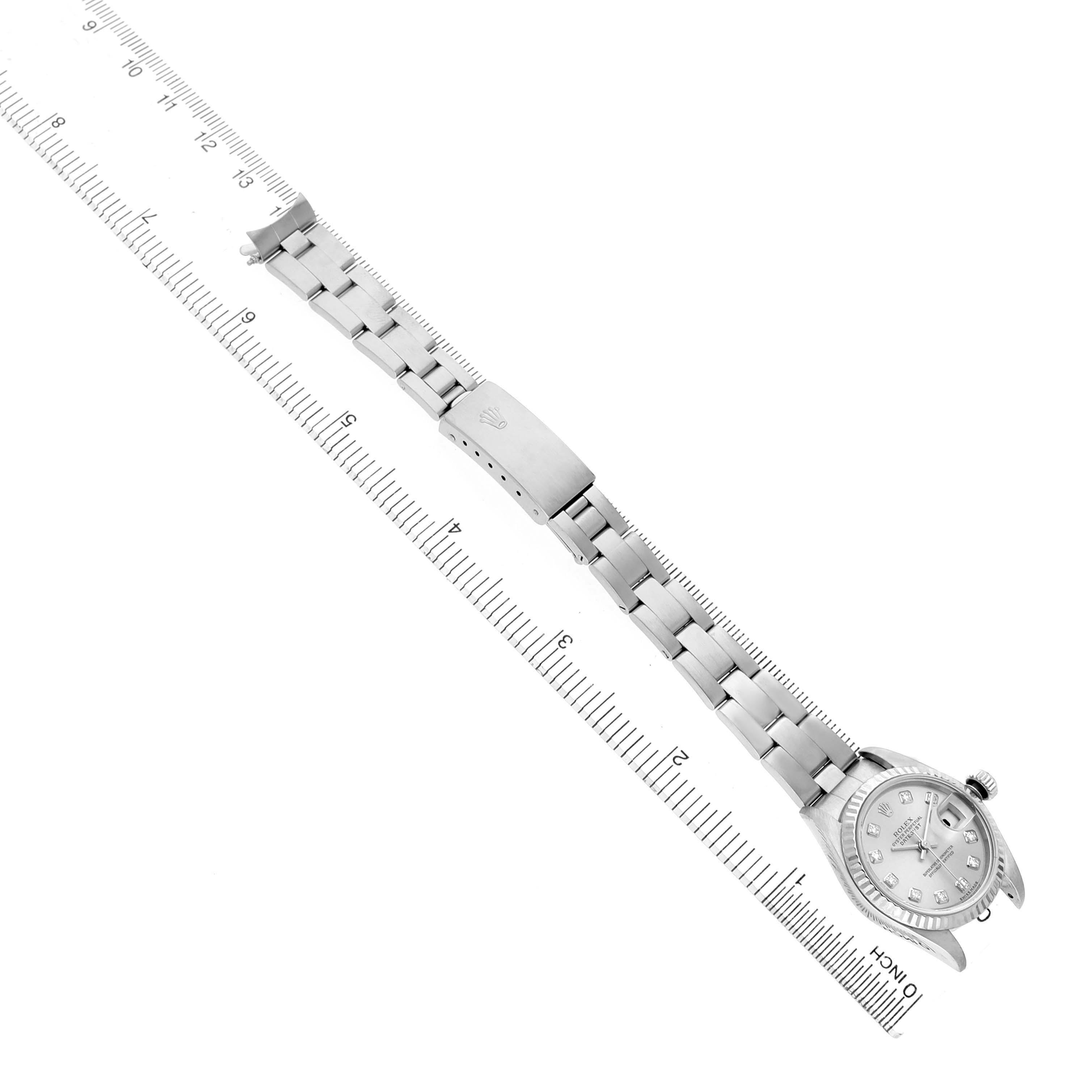 The Rolex Datejust 79174 Women's Stainless Steel Silver Dial watch is shown at an angled top view, displaying the bracelet and clasp alongside a ruler for scale.