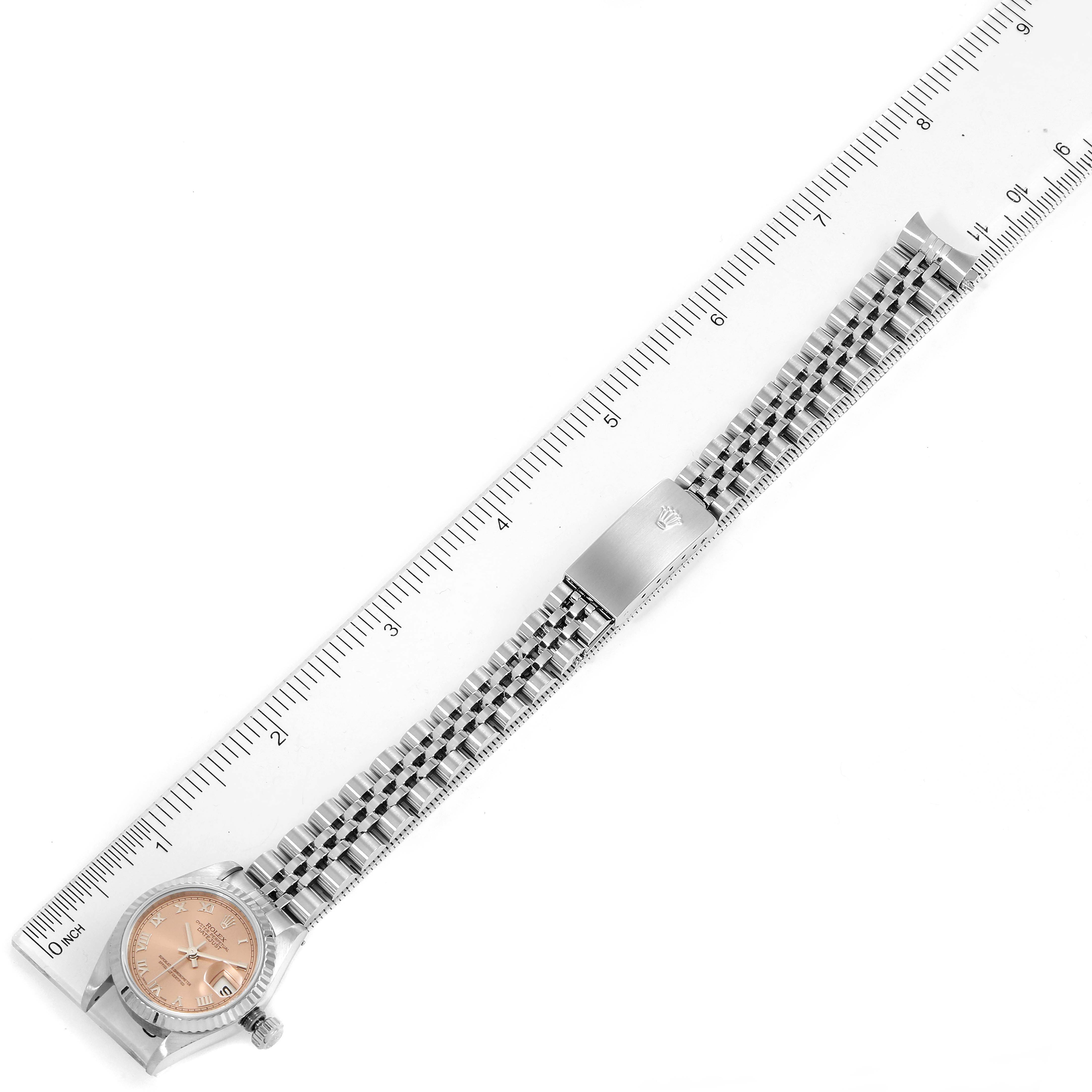 The image shows a top-down view of a Rolex Datejust 79174 Women's Stainless Steel Pink Dial 79174 Women's Stainless Steel Pink Dial watch, displaying the dial, bracelet, and clasp, alongside a ruler.