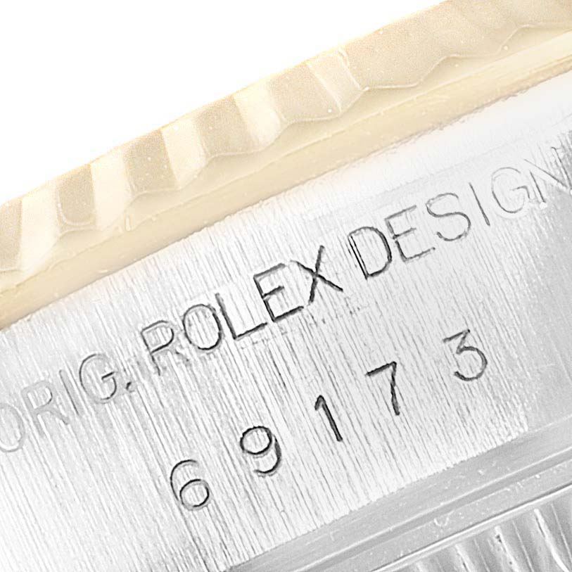 A close-up view of the Rolex Datejust 69173 Women
s Steel and Gold (two tone) Champagne Dial 69173 Women
s Steel and Gold (two tone) Champagne Dial bezel and case with engraved text reading "ORIG. ROLEX DESIGN 69173".