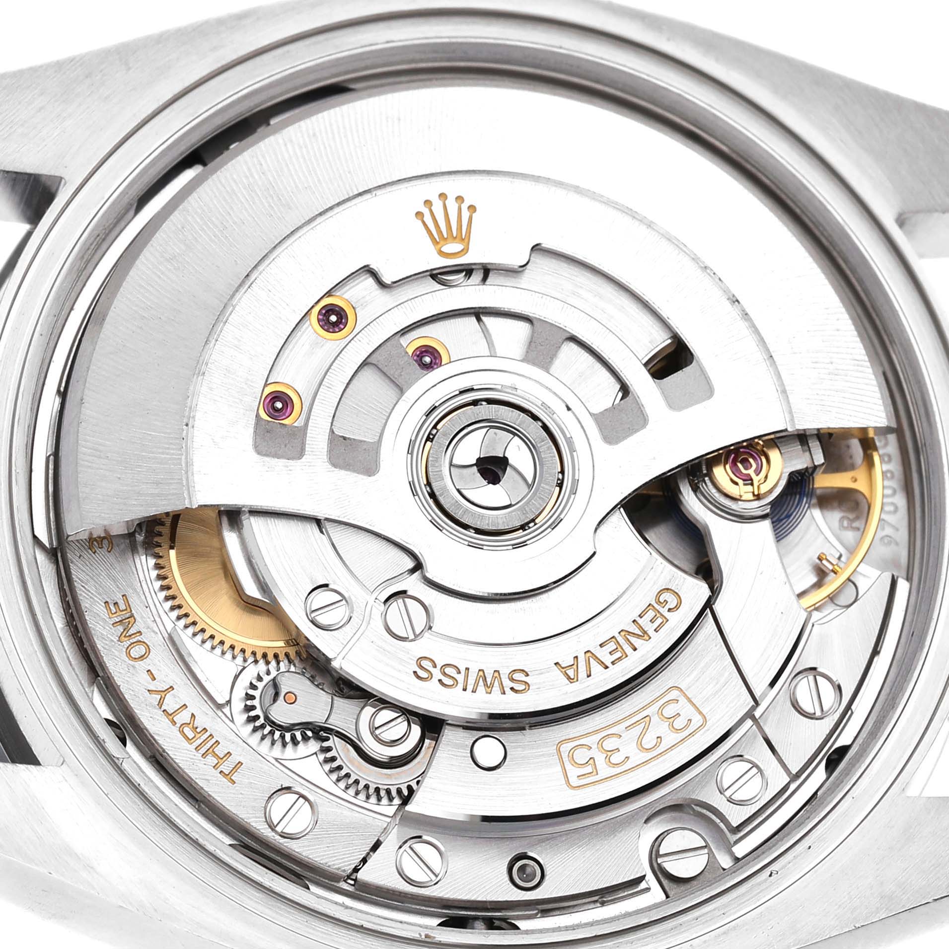 The image shows the inner mechanism of a Rolex Datejust 126200 Men's Stainless Steel Blue Dial watch, highlighting the rotor, gears, and markings from a top view.