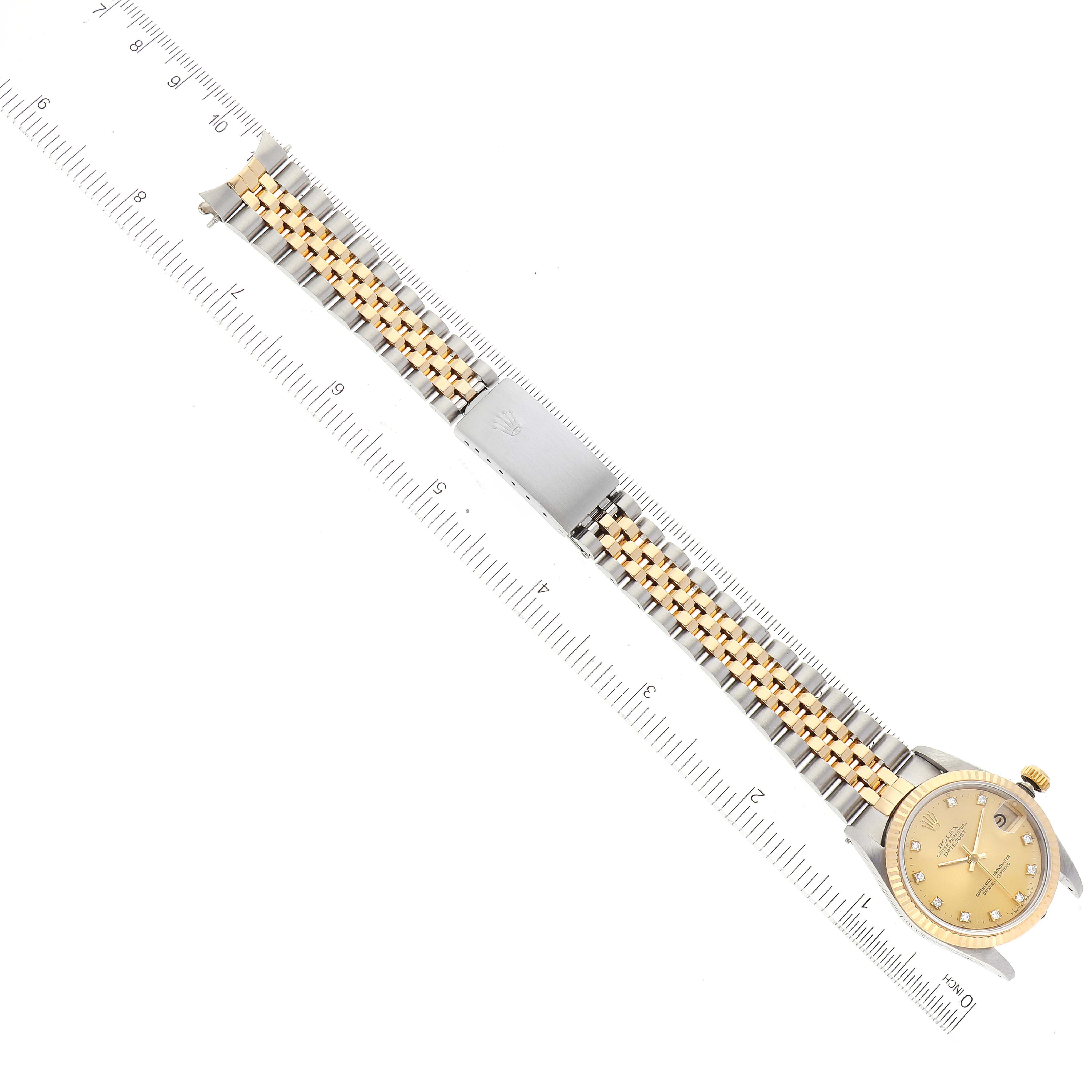 The image shows a top-down view of a Rolex Mid-Size 68273 Women
s Steel and Gold (two tone) Champagne Dial 68273 Women
s Steel and Gold (two tone) Champagne Dial watch with a two-tone bracelet beside a ruler for scale.