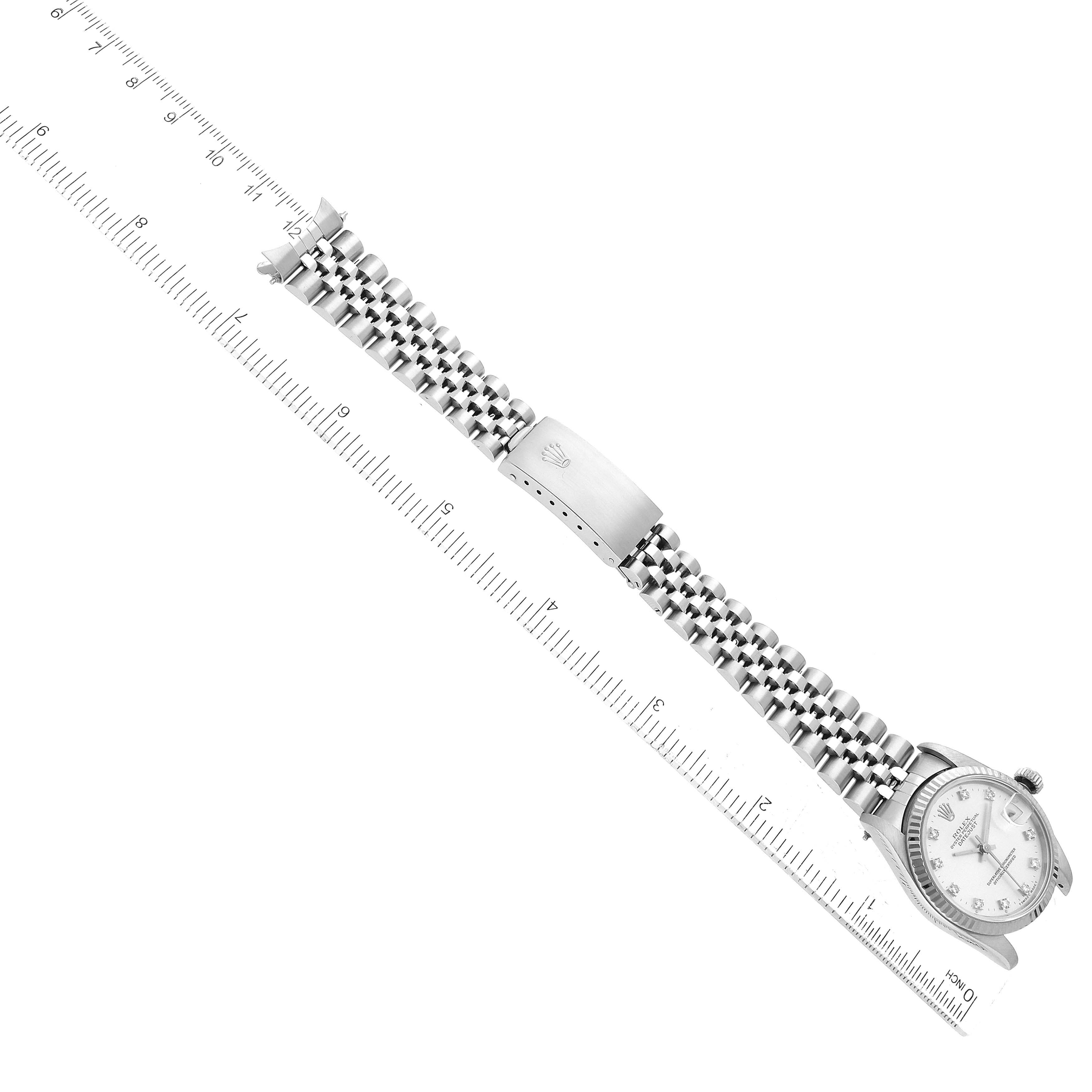 A diagonal top view of a Mid-Size Rolex watch showing the face, bracelet, and clasp next to a ruler.