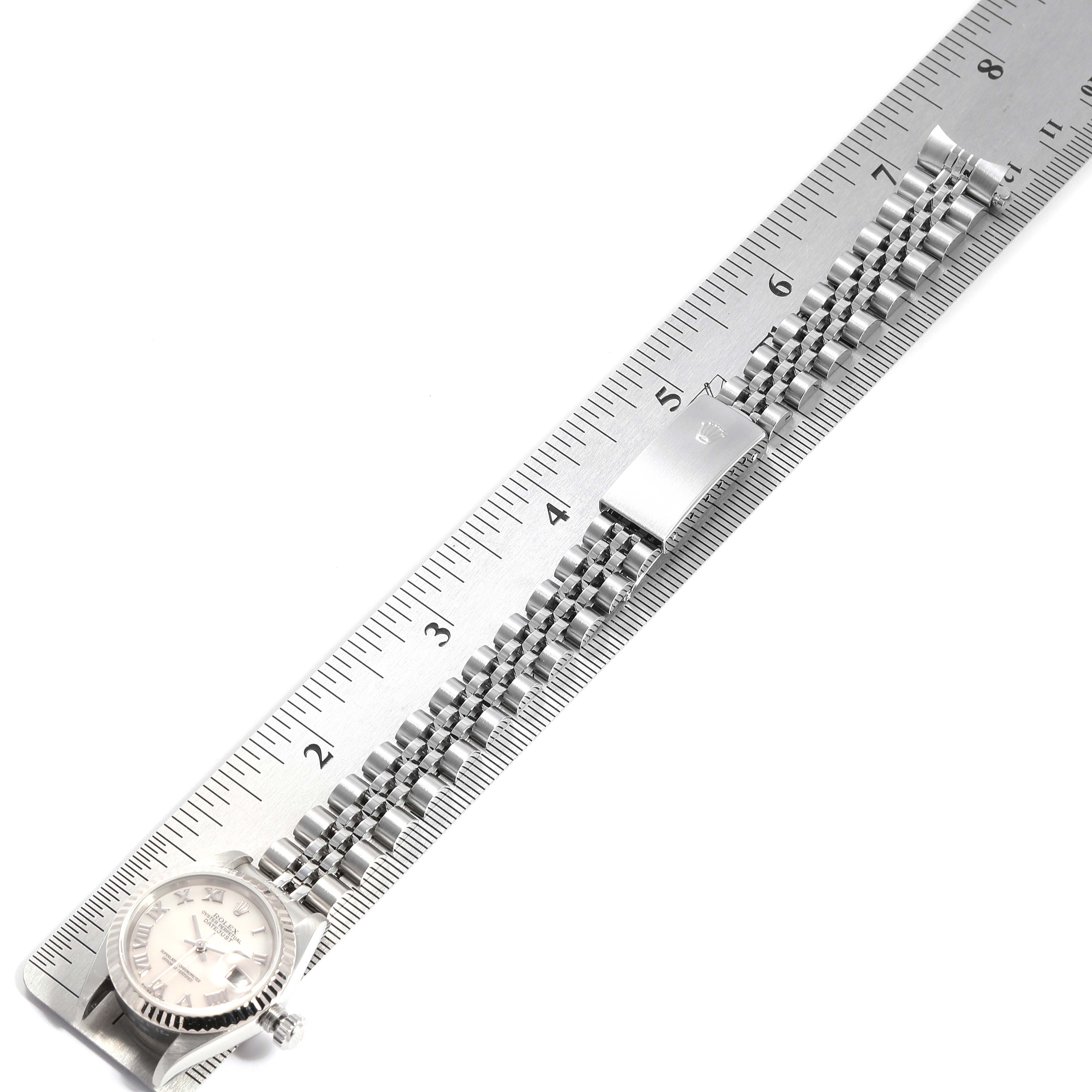 The image shows a Rolex Datejust 79174 Women
s Stainless Steel Mother of Pearl Dial 79174 Women
s Stainless Steel Mother of Pearl Dial watch and its bracelet, aligned with a ruler for measurement.
