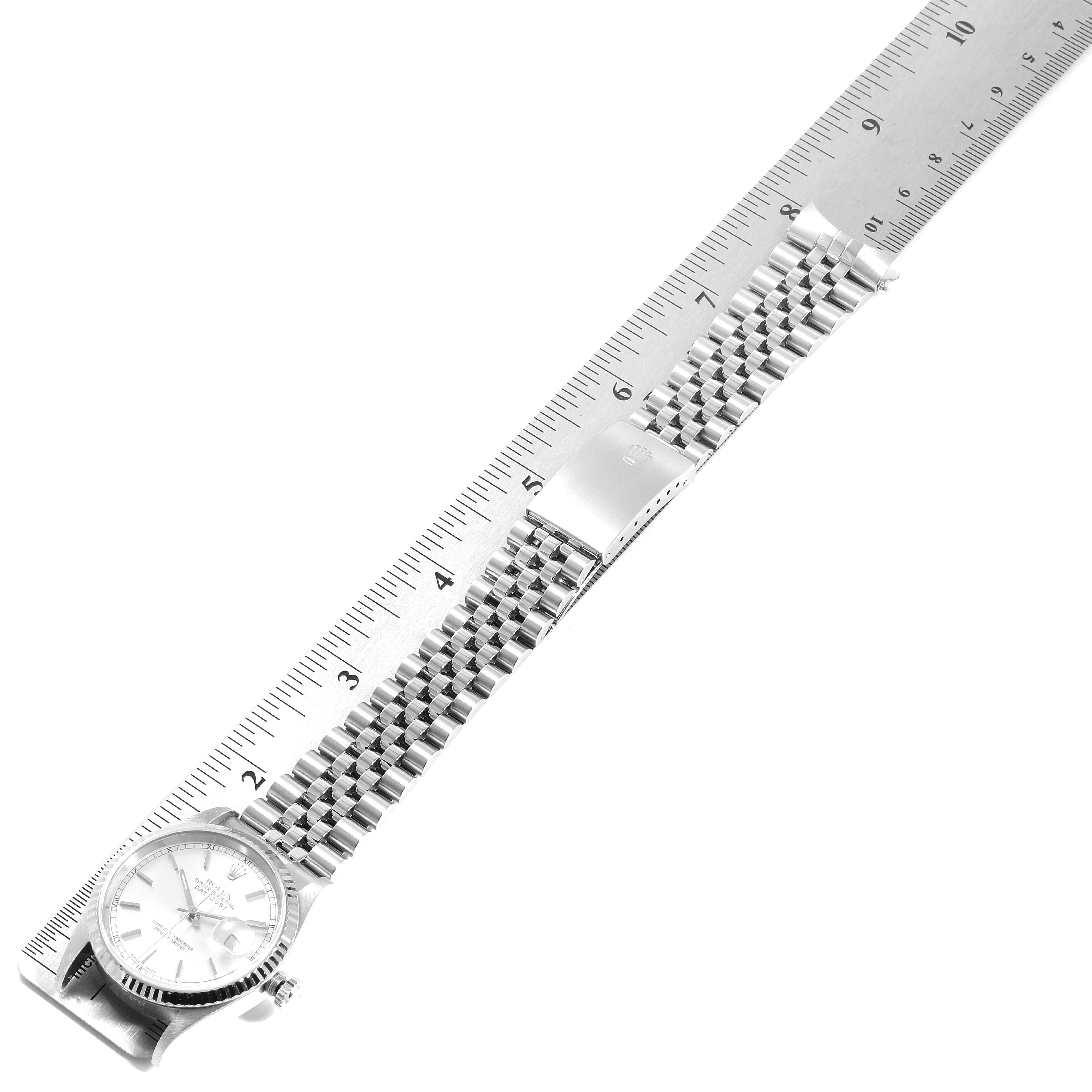 This is a top-down view of a Rolex Datejust 16234 Men's Stainless Steel Silver Dial 16234 Men's Stainless Steel Silver Dial watch, showing its face and full metal bracelet alongside a ruler.