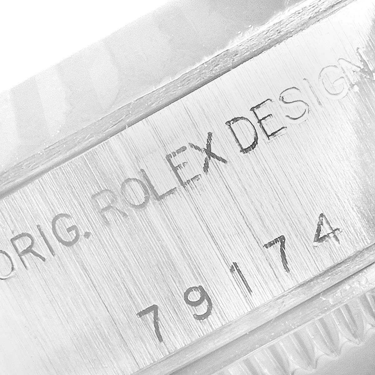 The image shows a close-up of the case side engraving on a Rolex Datejust 79174 Women
s Stainless Steel White Dial 79174 Women
s Stainless Steel White Dial model, displaying "ORIG. ROLEX DESIGN" and the number "79174."
