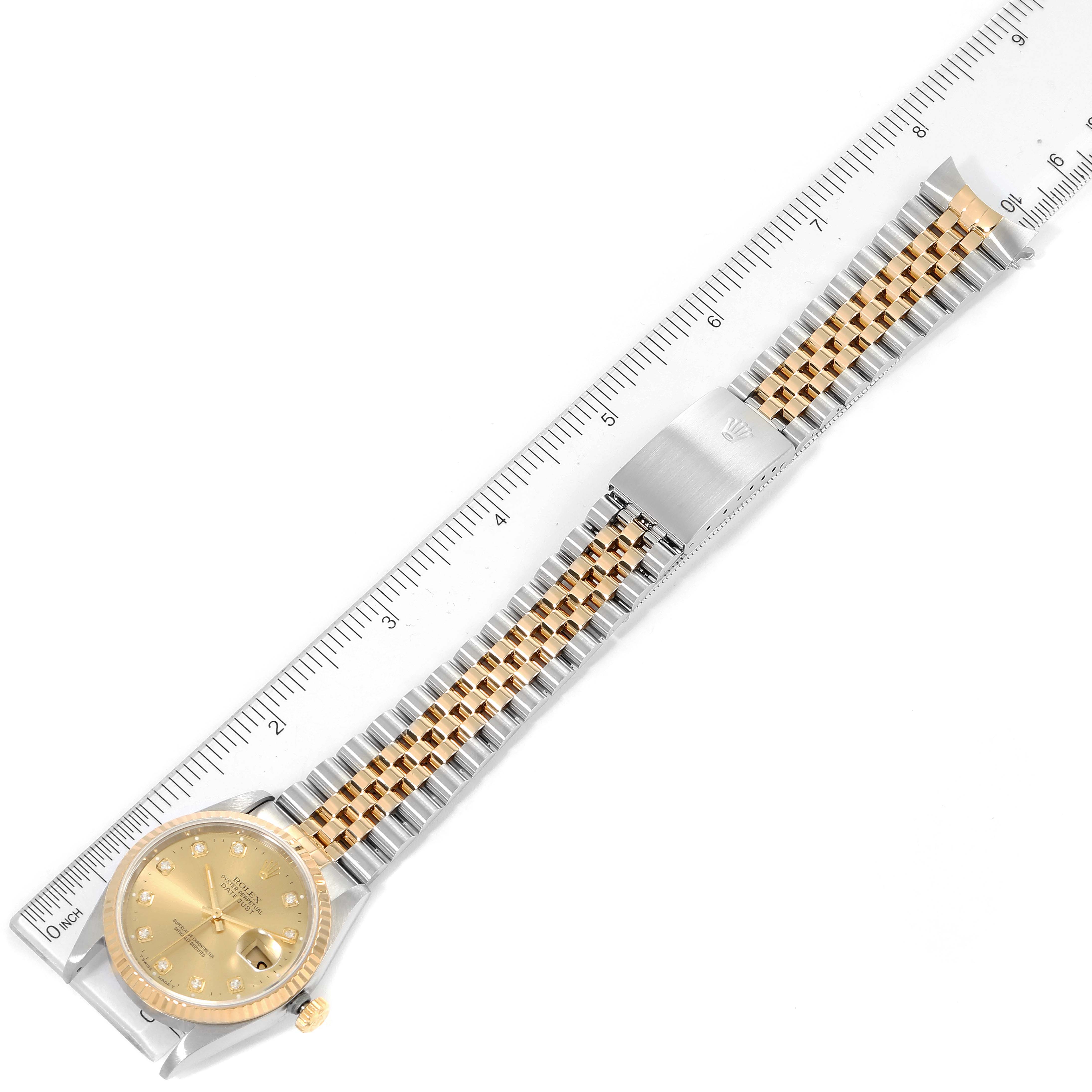 This image shows a top view of a Rolex Datejust 16233 Men's Steel and Gold (two tone) Champagne Dial 16233 Men's Steel and Gold (two tone) Champagne Dial watch with its gold and silver bracelet and a measuring ruler beside it.