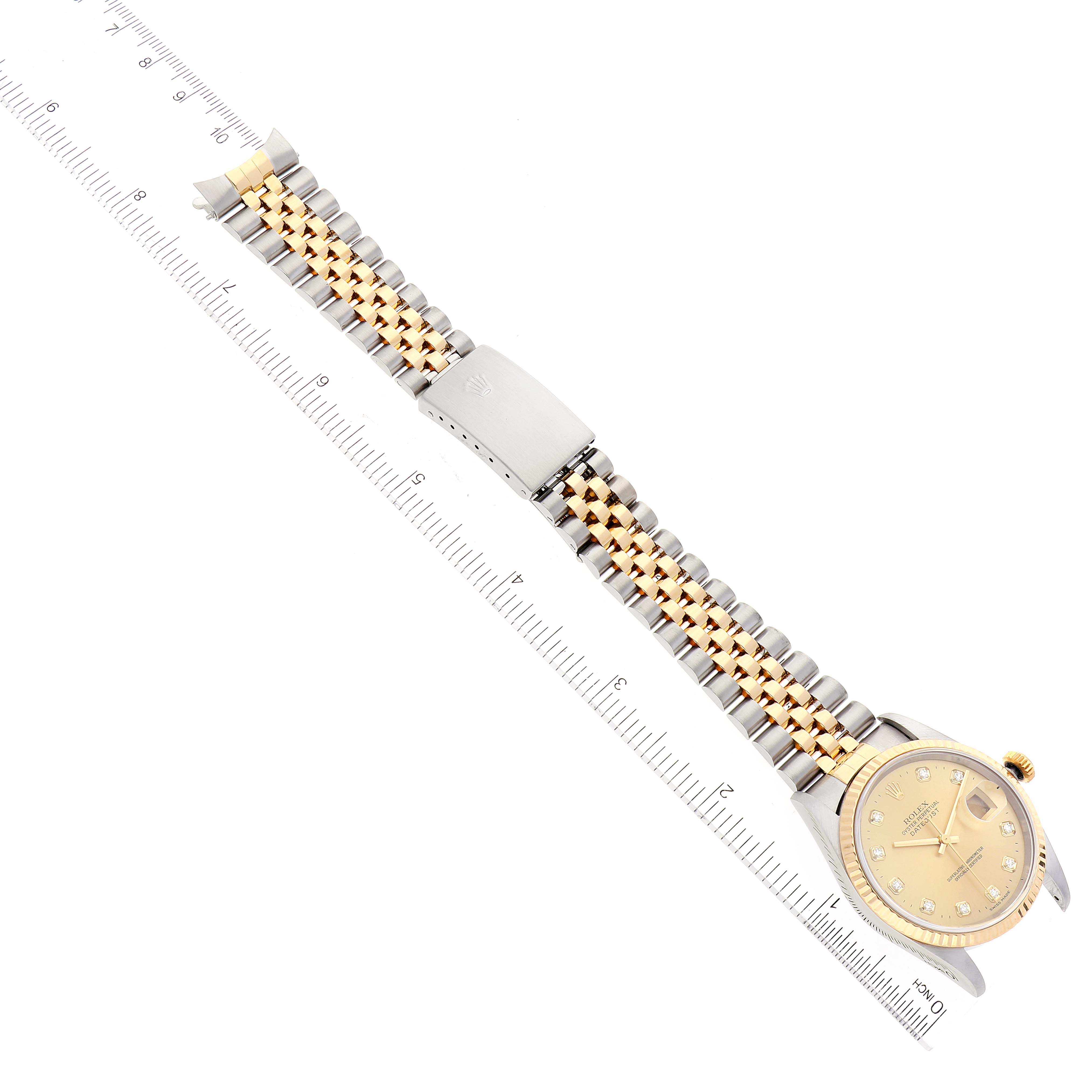 The image shows a Rolex Datejust 16233 Men's Steel and Gold (two tone) Champagne Dial 16233 Men's Steel and Gold (two tone) Champagne Dial watch from an overhead angle, highlighting the dial, bracelet, and clasp next to a ruler.