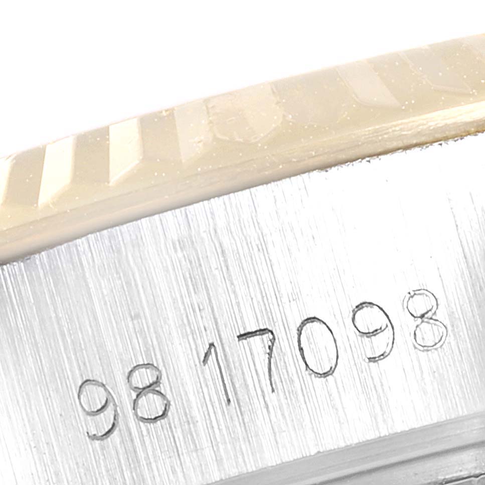 The image shows a close-up of the engraved serial number on a Rolex Datejust 69173 Women
s Steel and Gold (two tone) Champagne Dial 69173 Women
s Steel and Gold (two tone) Champagne Dial case and part of the fluted bezel.