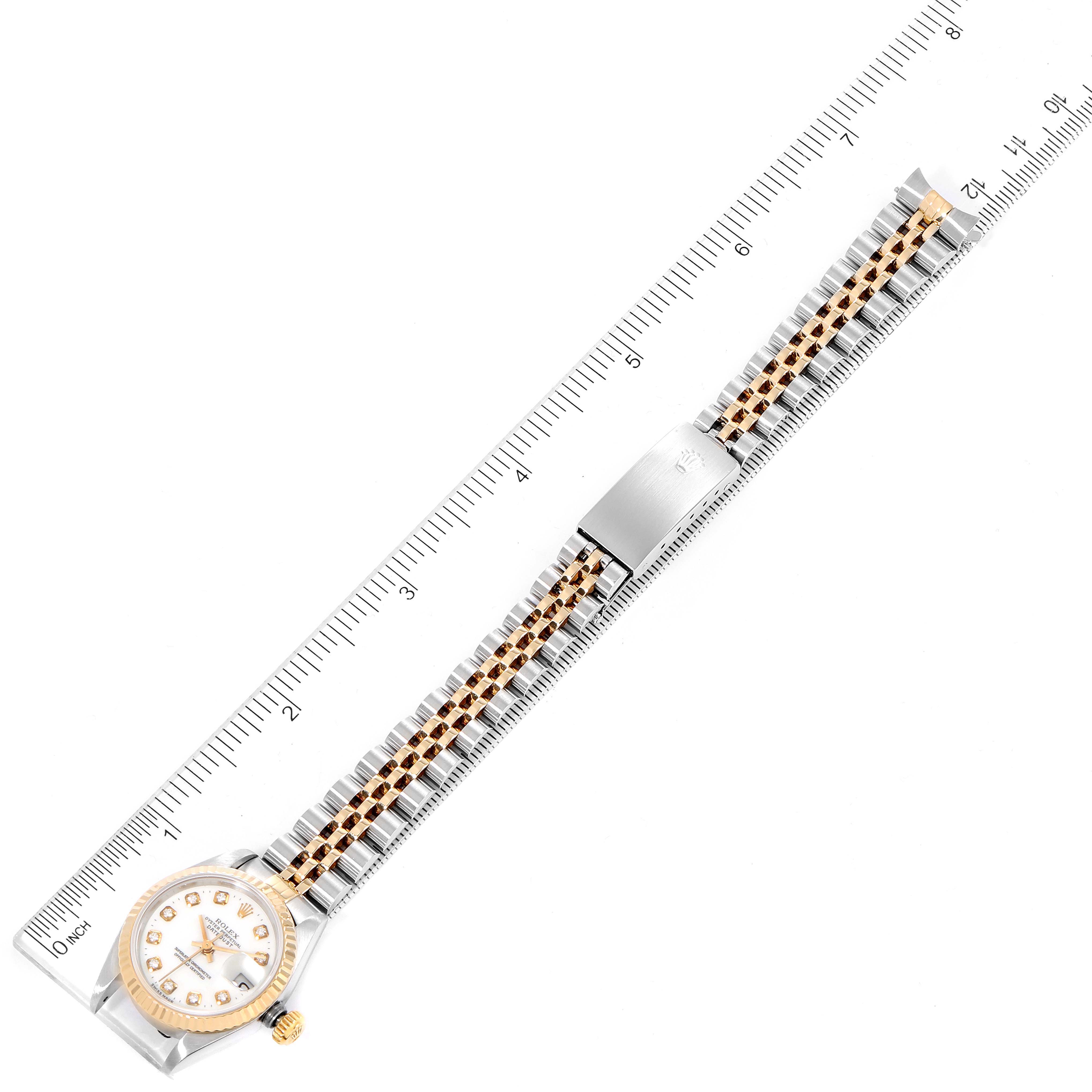 The image shows a top view of a Rolex Datejust 69173 Women
s Steel and Gold (two tone) White Dial 69173 Women
s Steel and Gold (two tone) White Dial watch, displaying the entire watch including the face, bezel, and band against a measuring ruler.