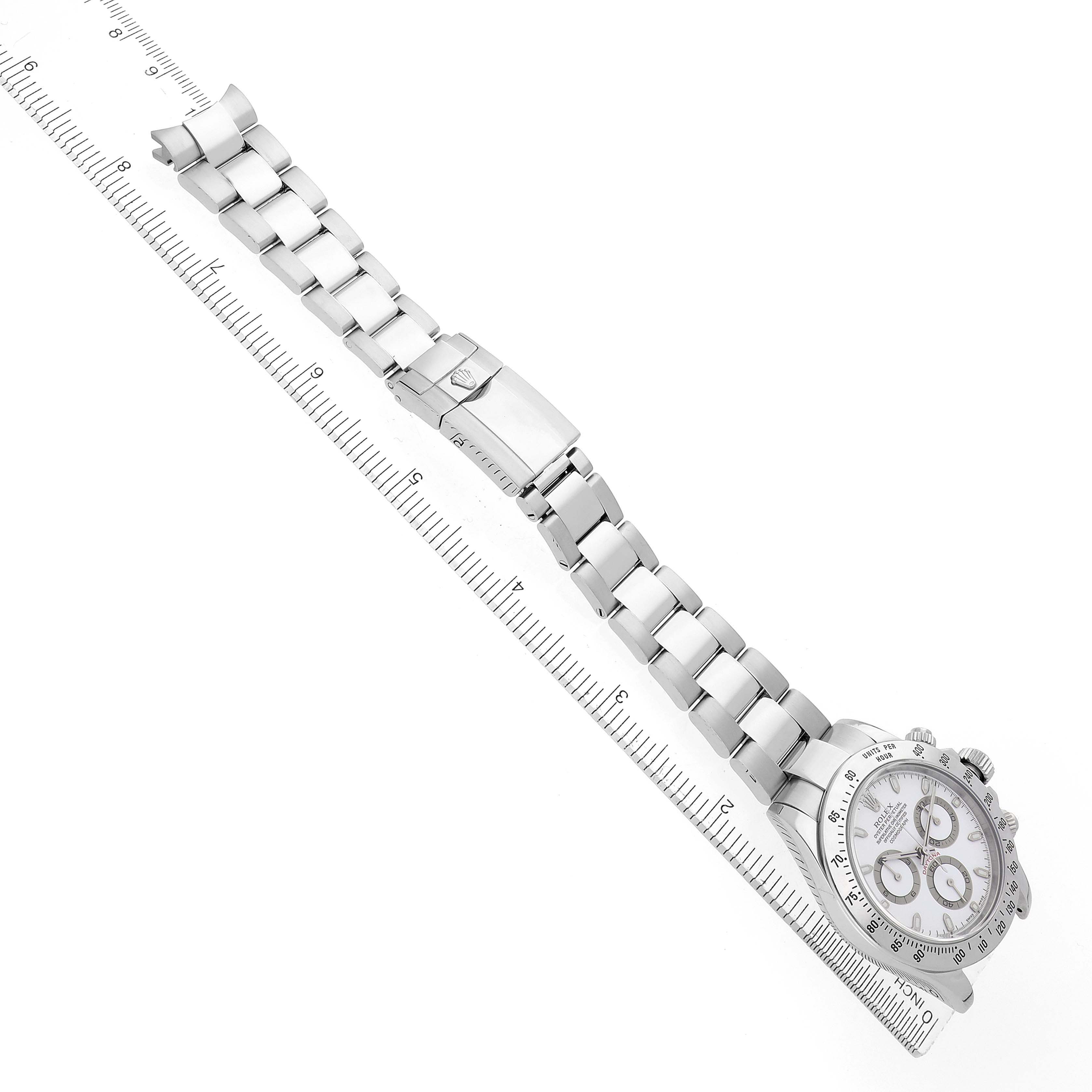 The image shows a Rolex Daytona model 116520 men's watch at an angle highlighting the bracelet, clasp, and face, aligned with a ruler for scale.