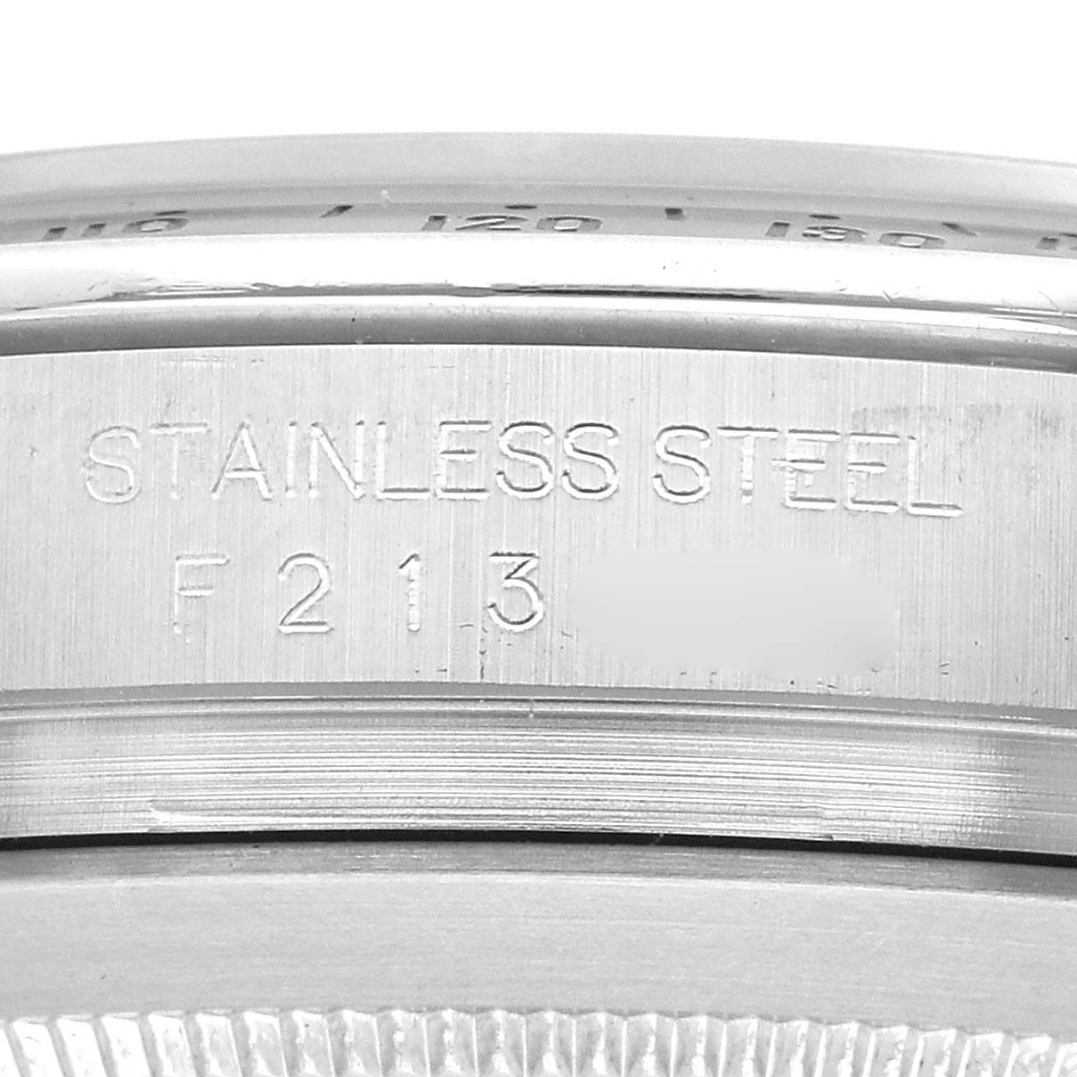 The image shows a close-up of the side of a Rolex Daytona model 116520, focusing on the engraved serial number on the stainless steel case.