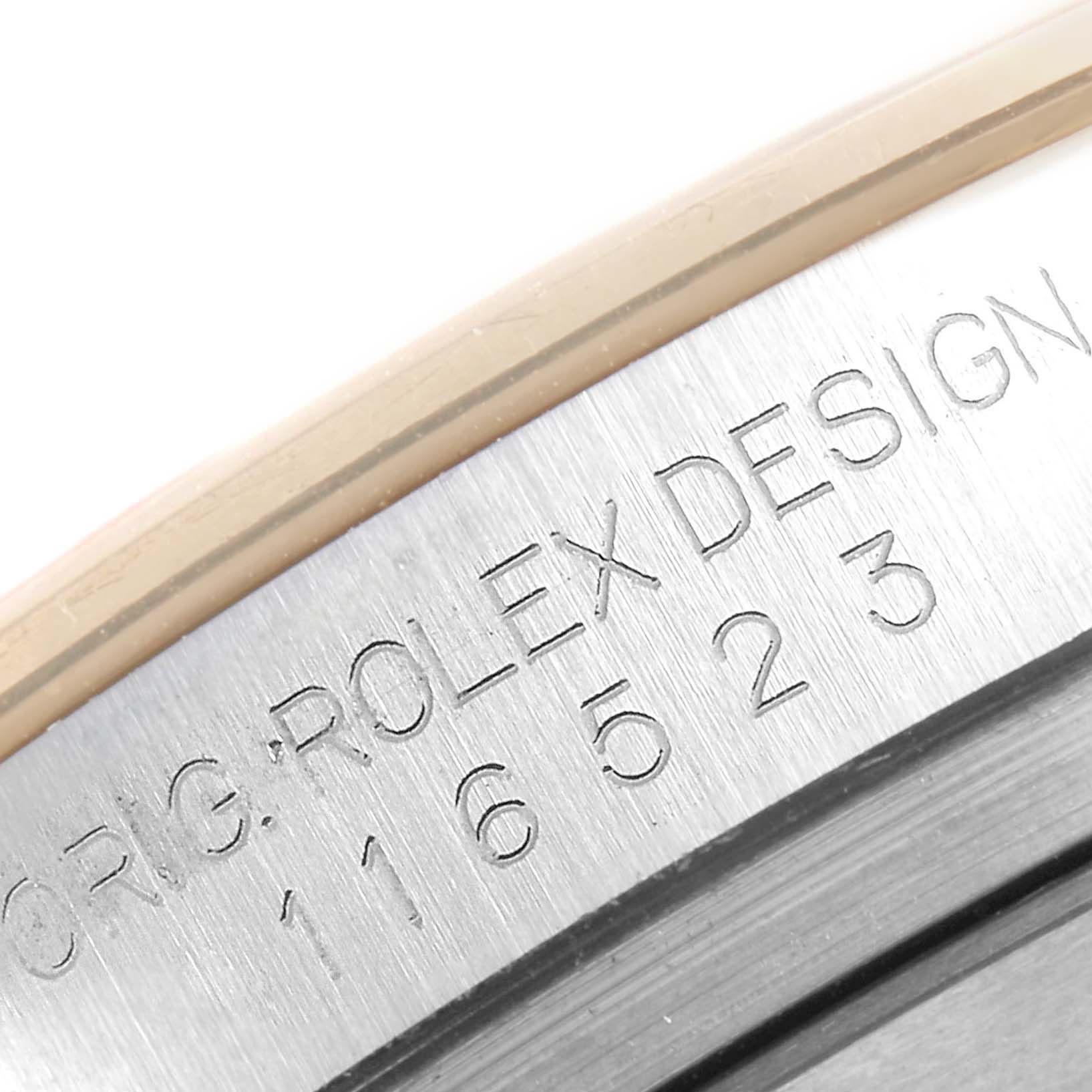 This close-up image shows the edge of a Rolex Daytona 116523 Men's Steel and Gold (two tone) Black Dial 116523 Men's Steel and Gold (two tone) Black Dial watch case with the model number engraved.