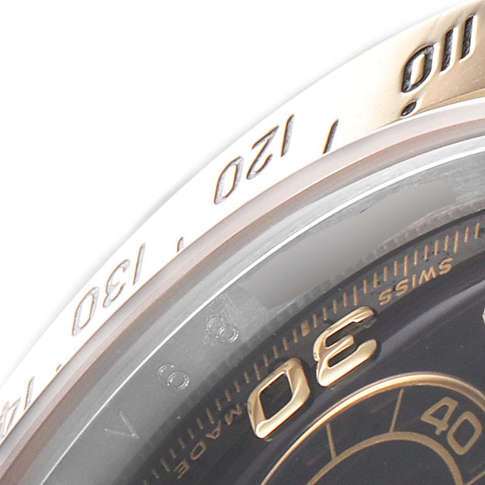 This close-up image shows the tachymeter bezel and part of the dial of a Rolex Daytona 116523 Men's Steel and Gold (two tone) Black Dial 116523 Men's Steel and Gold (two tone) Black Dial watch.
