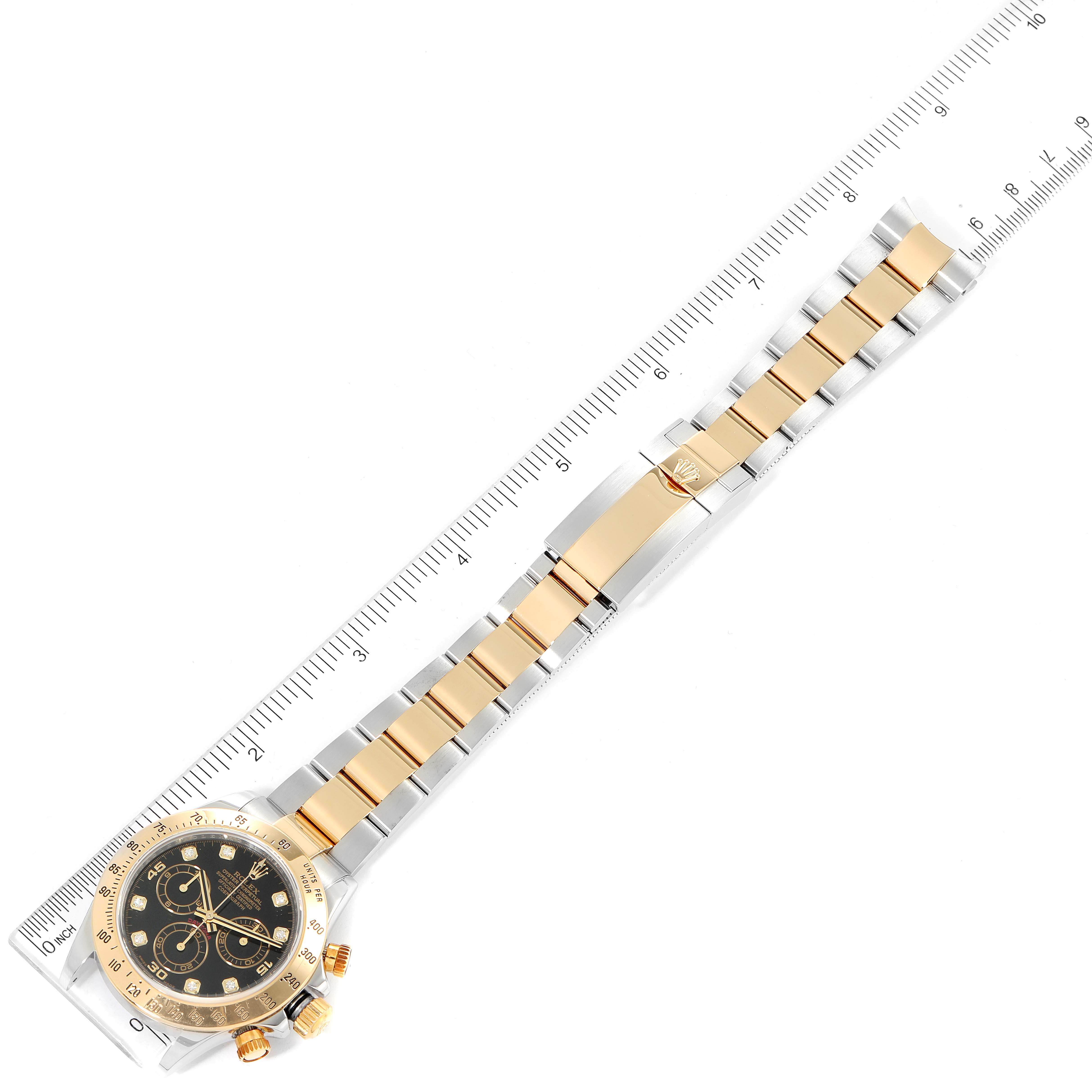 The image shows a top-down view of a Rolex Daytona 116523 Men's Steel and Gold (two tone) Black Dial 116523 Men's Steel and Gold (two tone) Black Dial watch with its band measured against a ruler.
