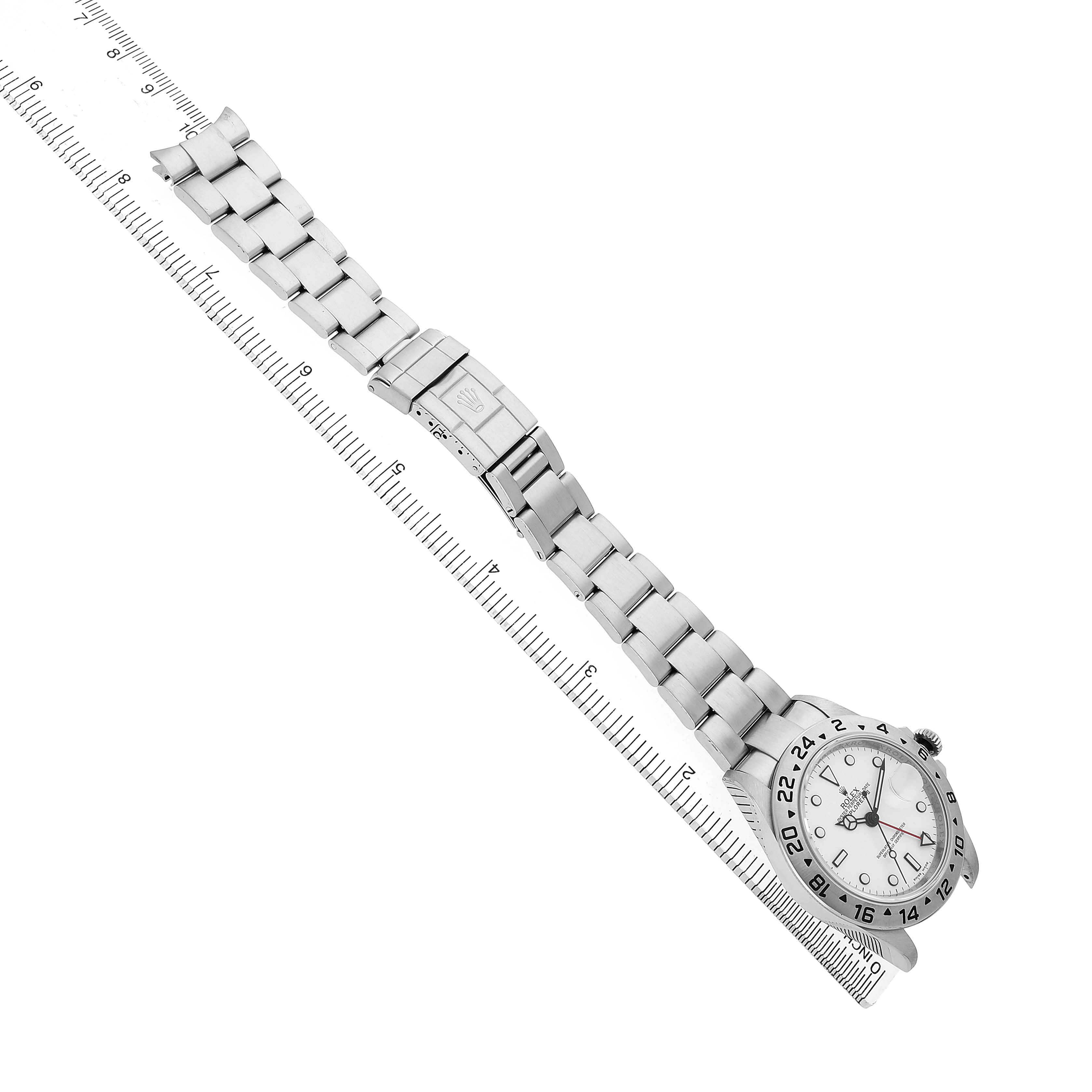 The Rolex Explorer 16570 T Men's Stainless Steel White Dial watch is shown at a tilted angle, displaying the bracelet and clasp alongside a measuring ruler.
