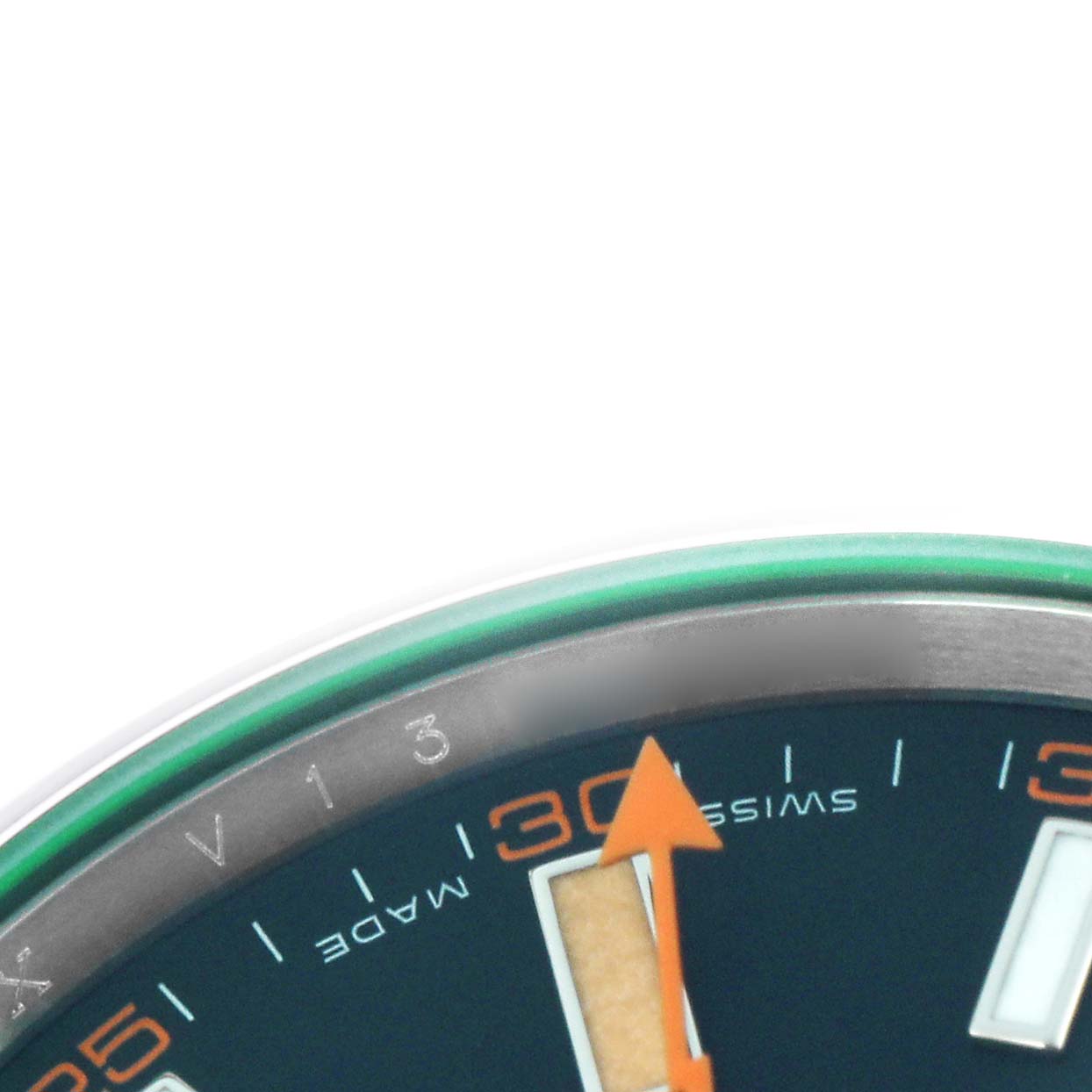 The image shows a close-up of the Rolex Milgauss 116400GV watch, focusing on the dial edge, green crystal, and orange lightning bolt second hand from an angled perspective.