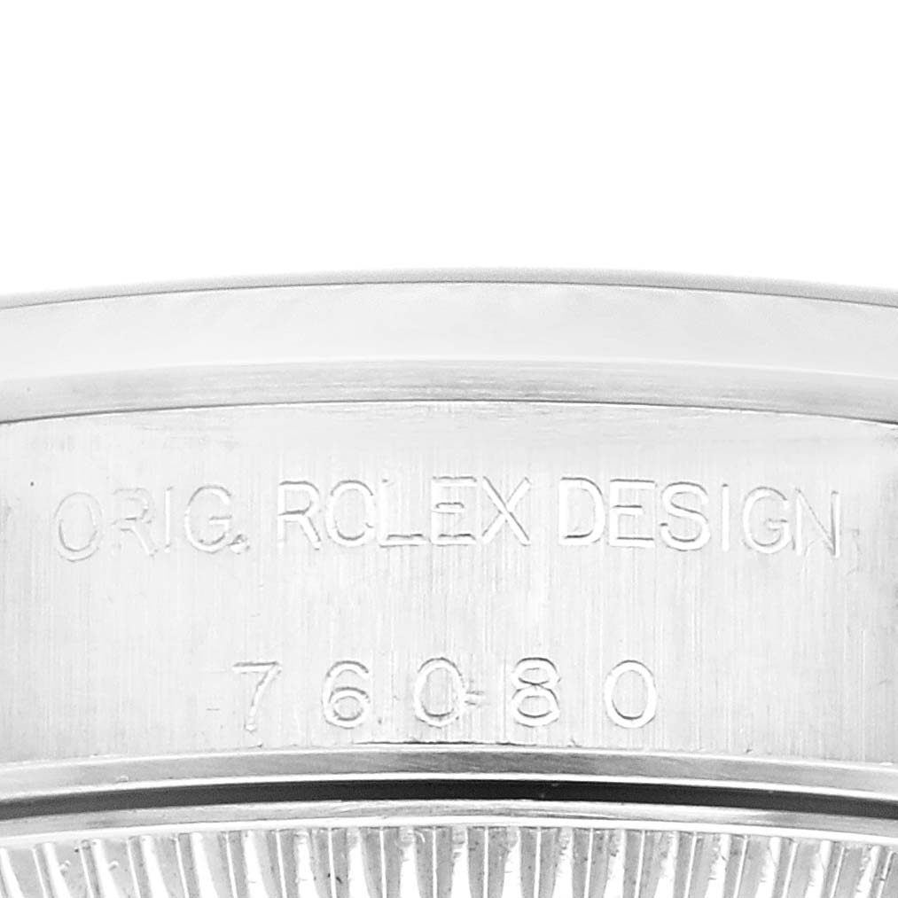 This is a close-up view of the side of the Rolex Oyster Perpetual 76080 Women's Stainless Steel Blue Dial 76080 Women's Stainless Steel Blue Dial watch case, showing engraved text and serial number.