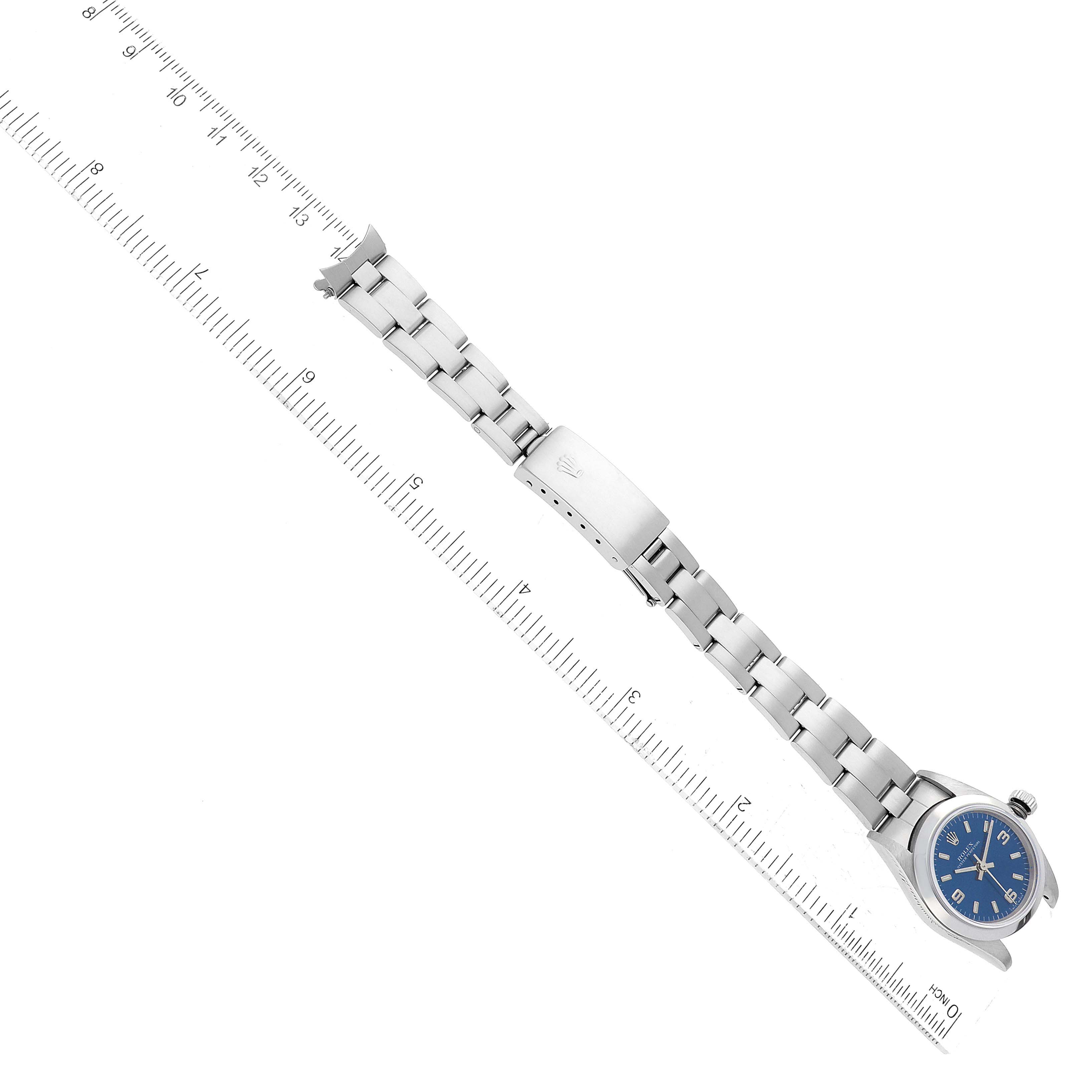 The Rolex Oyster Perpetual 76080 Women's Stainless Steel Blue Dial 76080 Women's Stainless Steel Blue Dial watch is shown fully extended with a ruler for scale, displaying the face, bracelet, and clasp.