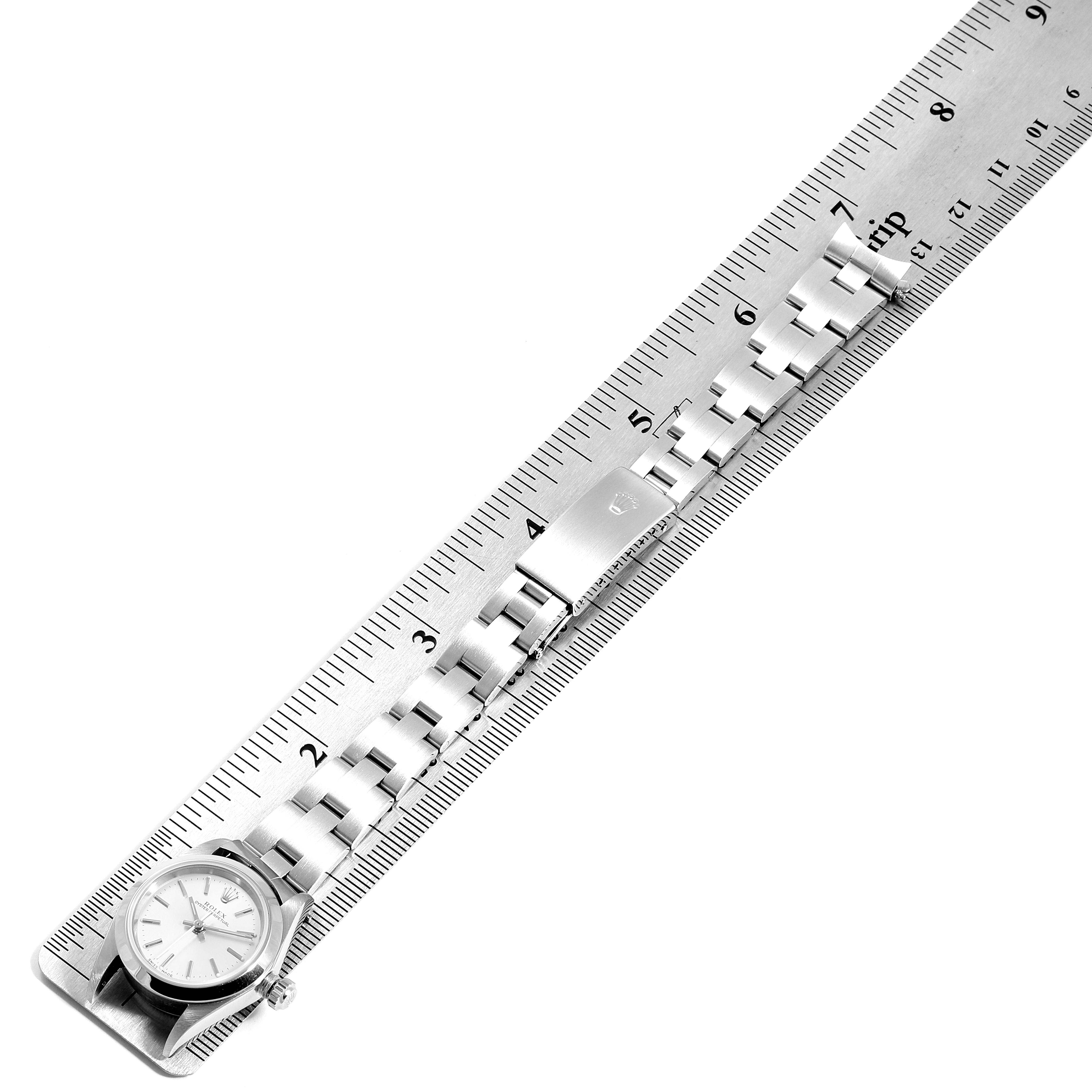 The image shows a Rolex Oyster Perpetual 76080 Women's Stainless Steel Silver Dial 76080 Women's Stainless Steel Silver Dial watch laid flat under a ruler, displaying the watch's face and bracelet.