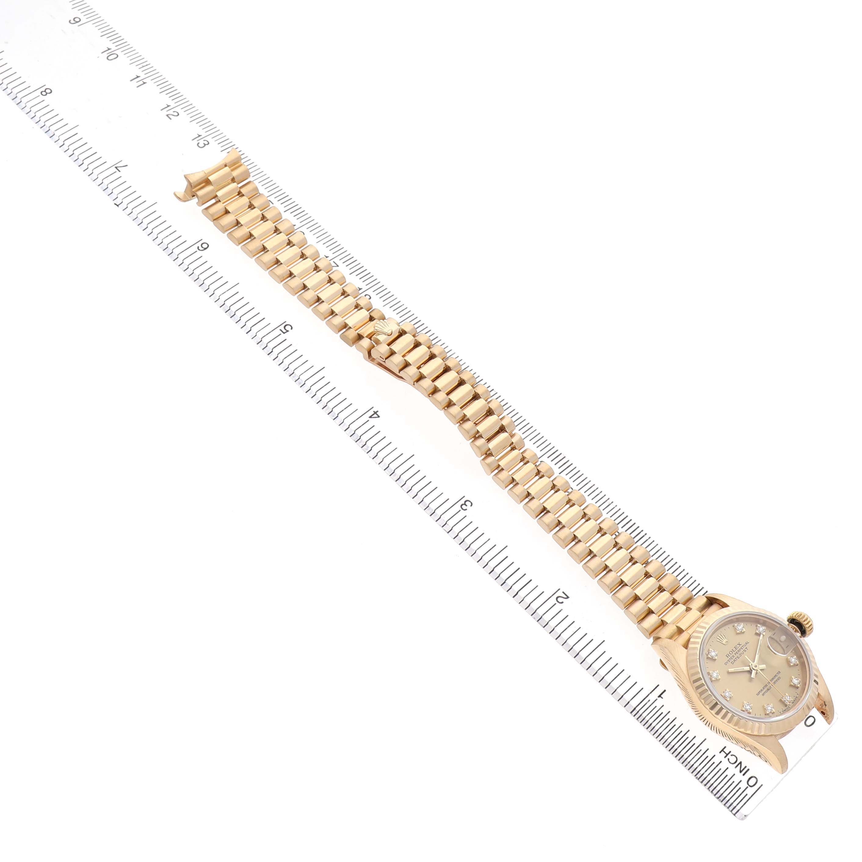 The image shows a Rolex President 69178 Women's Yellow Gold Champagne Dial model watch from a top-down angle, highlighting the gold bracelet and dial, beside a ruler for scale.