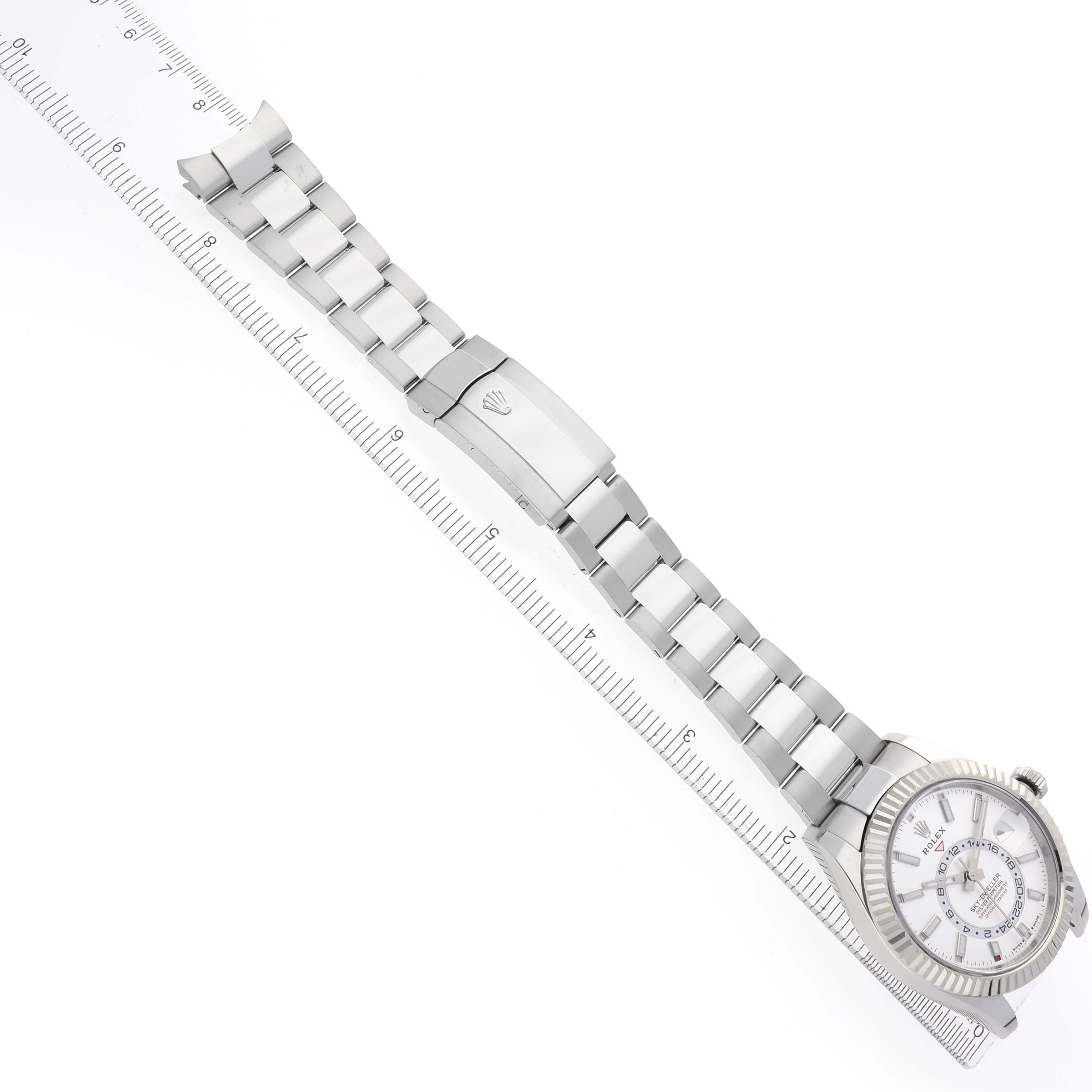 The image shows a Rolex Sky-Dweller model 336934 men's watch, displayed diagonally, featuring its full bracelet, clasp, and watch face alongside a ruler.