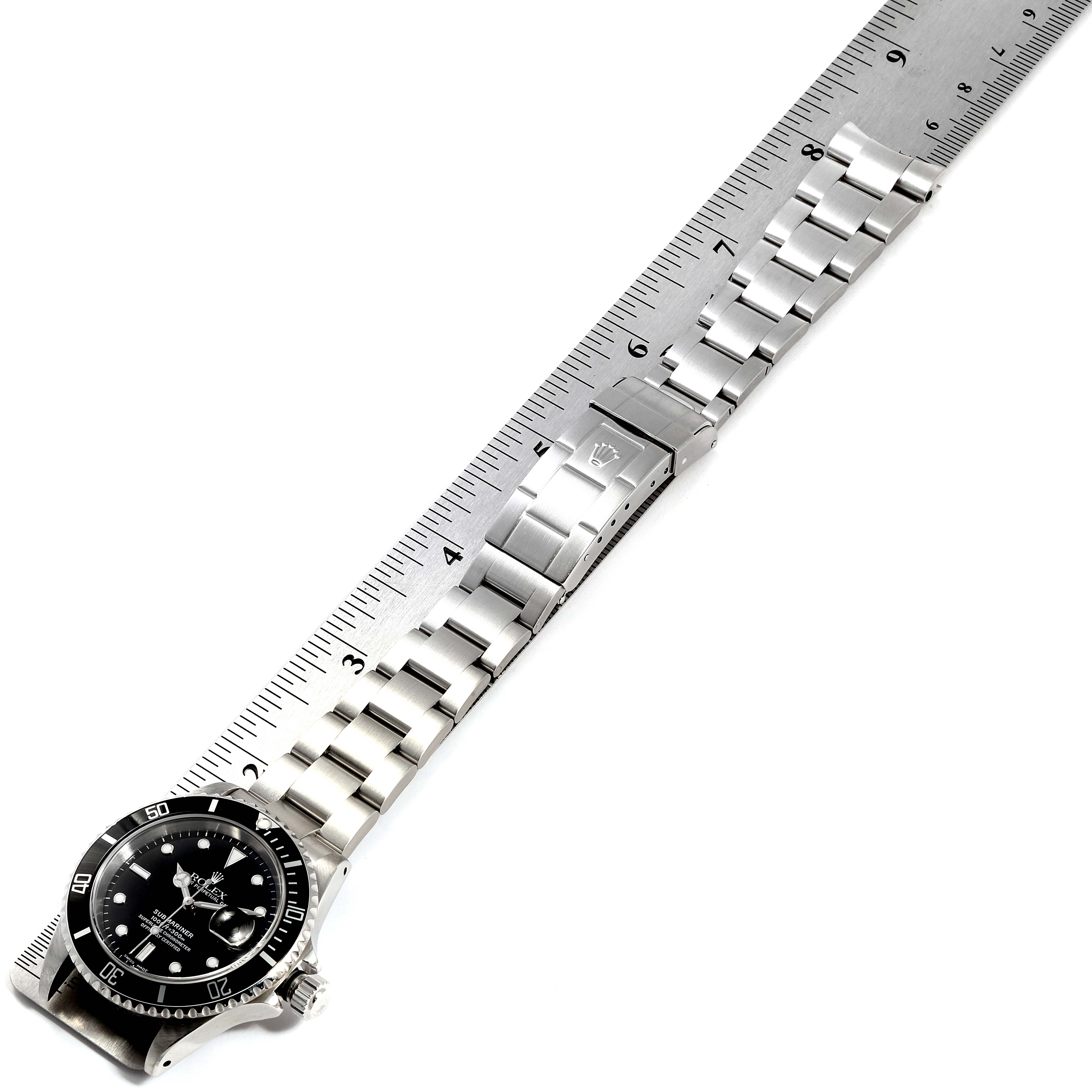 The image shows a top-down view of a Rolex Submariner 16610 Men
s Stainless Steel Black Dial 16610 Men
s Stainless Steel Black Dial watch, highlighting its face, bezel, and stainless steel bracelet with a ruler beside it.