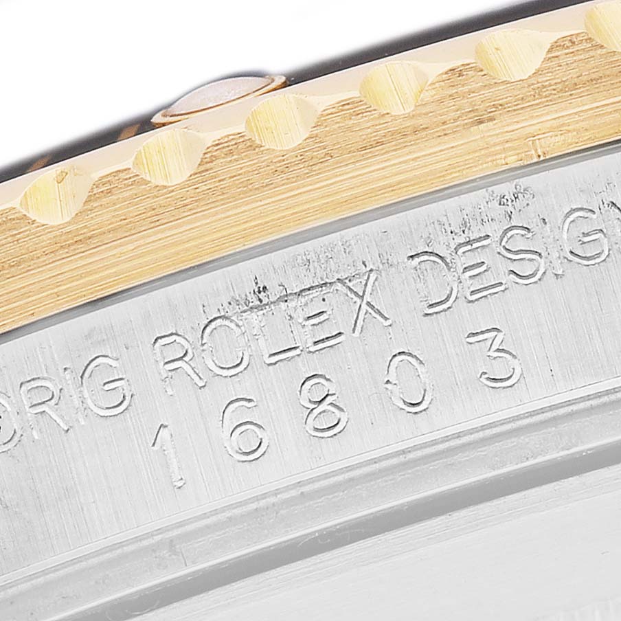 The image shows a close-up of the bezel and case side with the engraved model number of a Rolex Submariner 16803 Men's Steel and Gold (two tone) Black Dial watch.