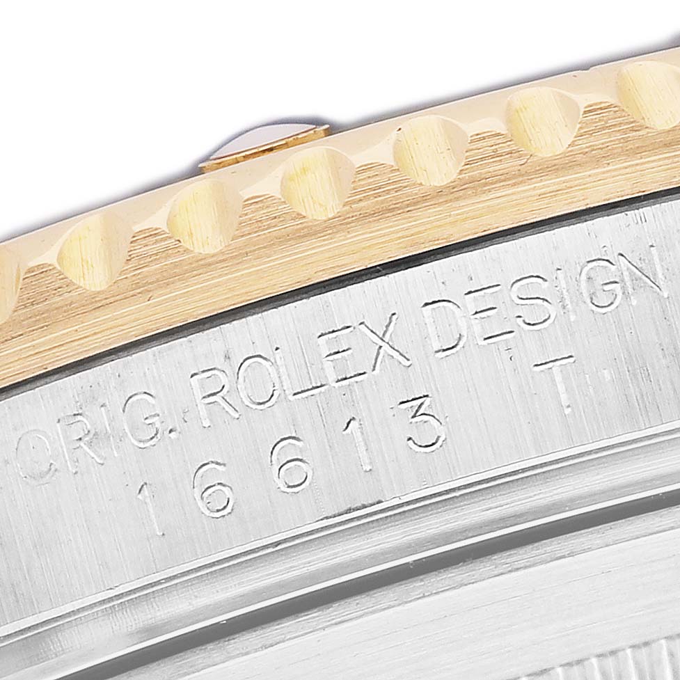 The image shows a close-up of the Rolex Submariner 16613LB Men's Steel and Gold (two tone) Blue Dial's bezel and engraved model number on the case side.