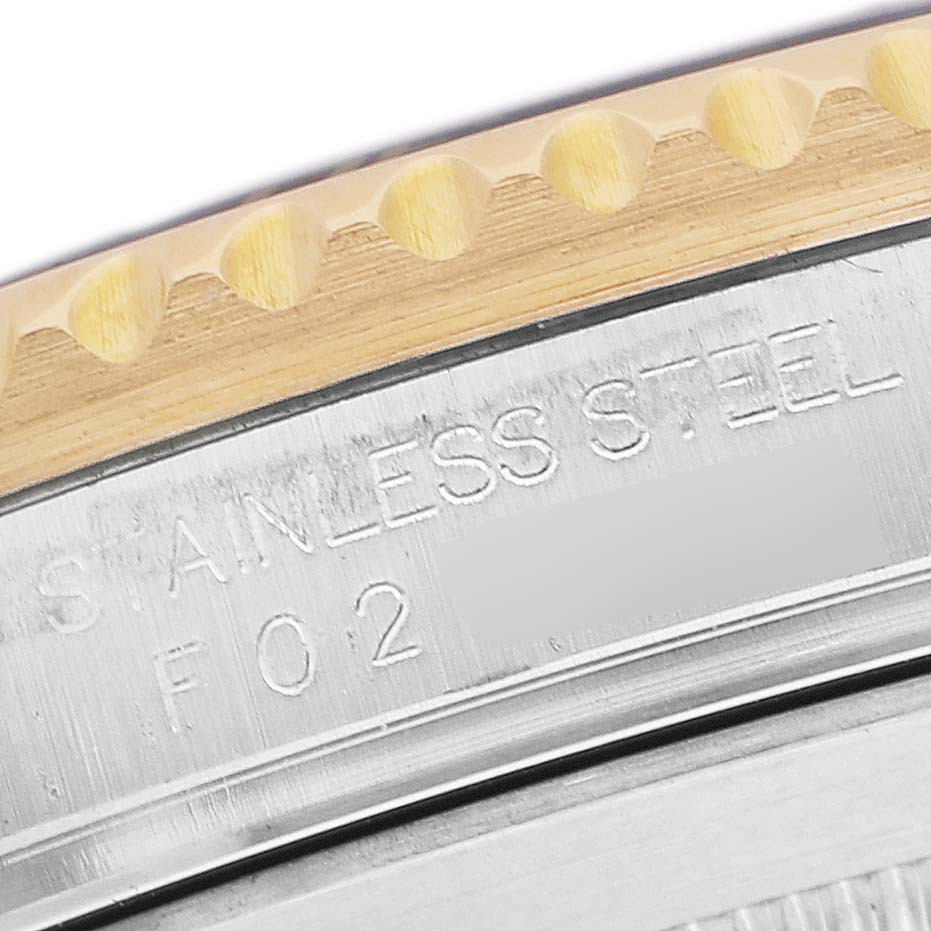 The image shows a close-up of the stainless steel case back and bezel edge of a Rolex Submariner 16613LB Men's Steel and Gold (two tone) Blue Dial watch.